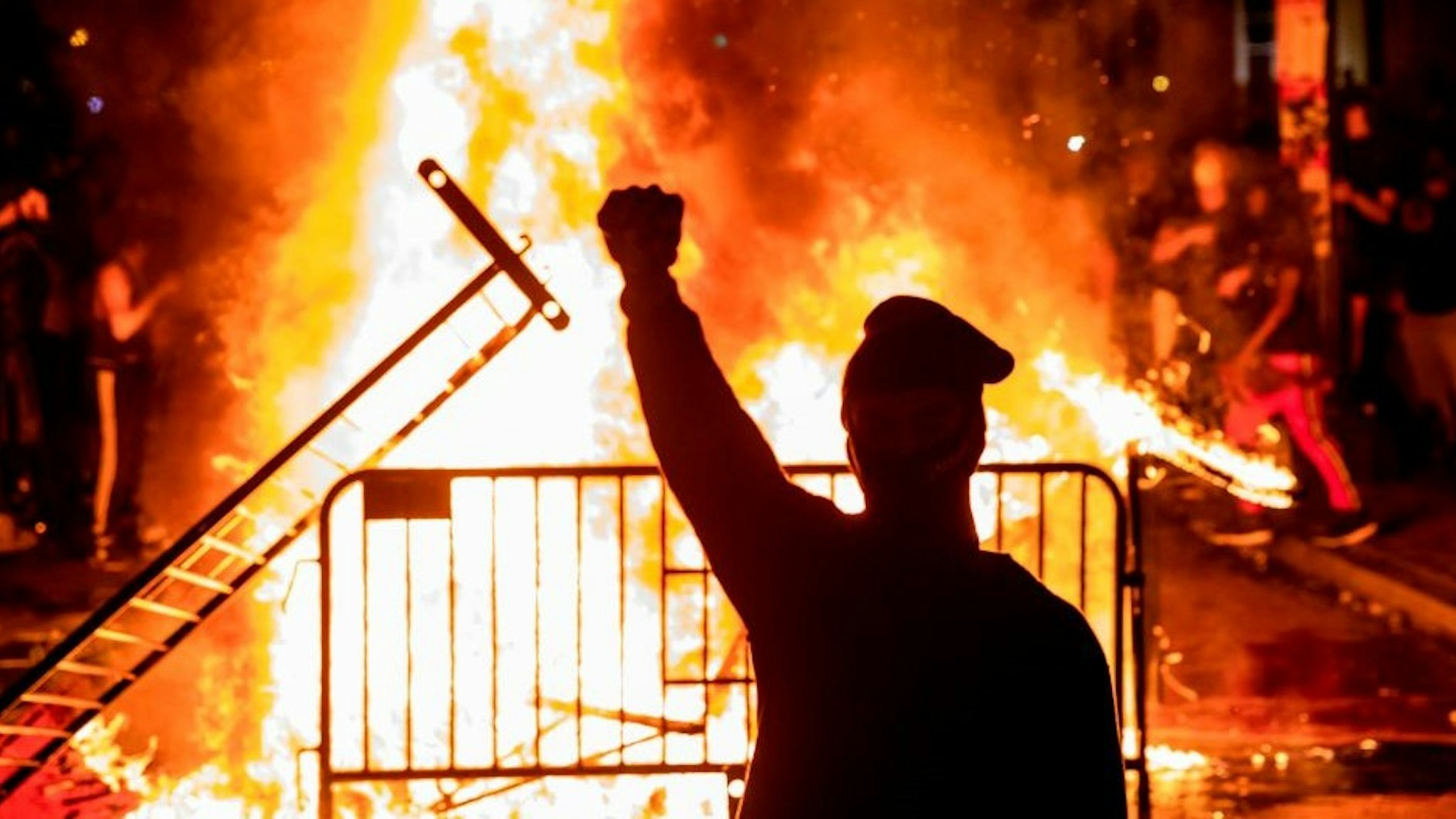 TOPSHOT - A protester raises a fist near a fire during a demonstration outside the White House over the death of George Floyd at the hands of Minneapolis Police in Washington, DC, on May 31, 2020. - Thousands of National Guard troops patrolled major US cities after five consecutive nights of protests over racism and police brutality that boiled over into arson and looting, sending shock waves through the country. The death Monday of an unarmed black man, George Floyd, at the hands of police in Minneapolis ignited this latest wave of outrage in the US over law enforcement's repeated use of lethal force against African Americans -- this one like others before captured on cellphone video. (Photo by Samuel Corum / AFP) (Photo by S