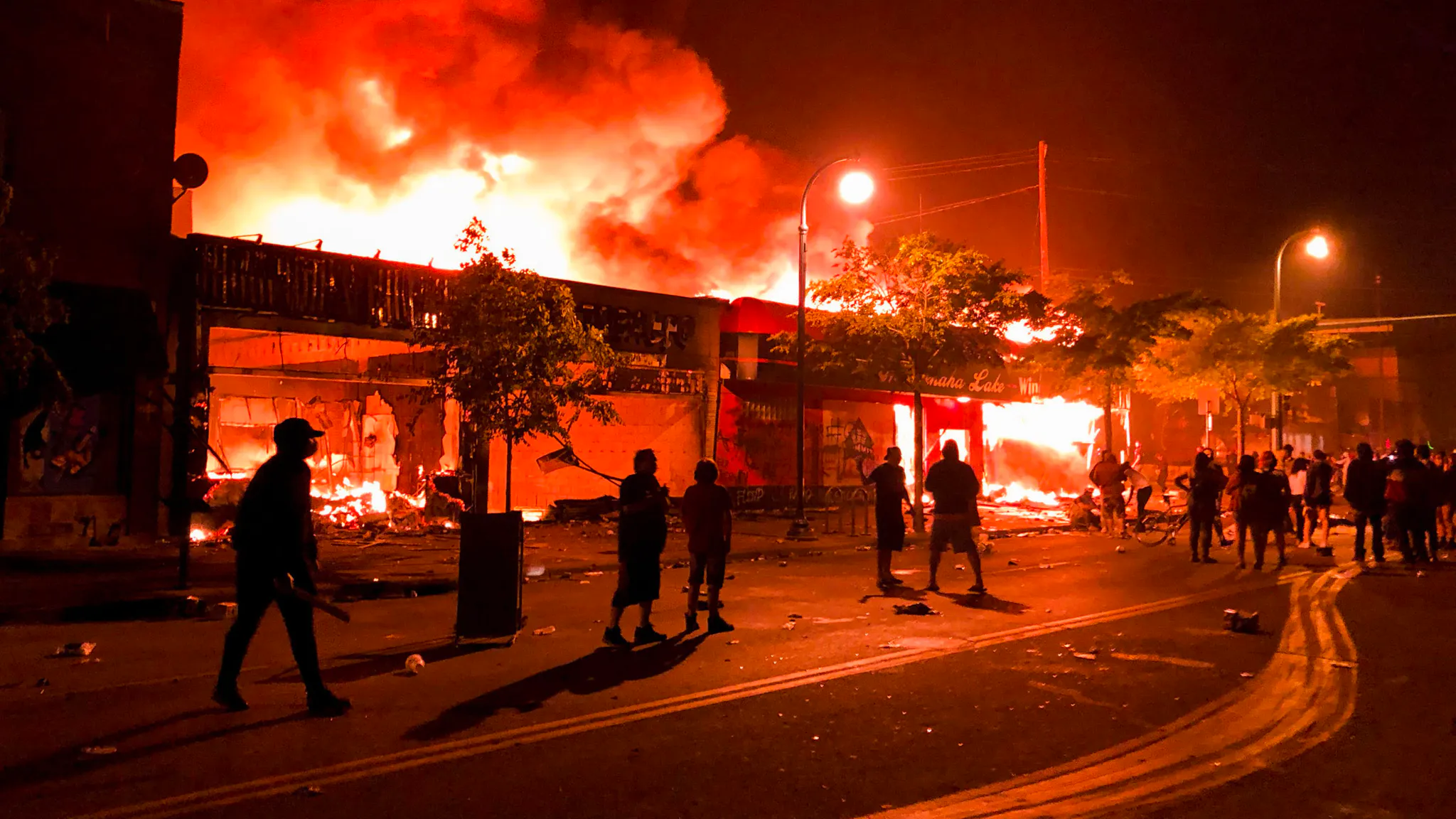 TOPSHOT-US-POLITICS-POLICE-JUSTICE-RACE TOPSHOT - Flames rise from a liquor store and shops near the Third Police Precinct on May 28, 2020 in Minneapolis, Minnesota, during a protest over the death of George Floyd, an unarmed black man, who died after a police officer kneeled on his neck for several minutes. - A police precinct in Minnesota went up in flames late on May 28 in a third day of demonstrations as the so-called Twin Cities of Minneapolis and St. Paul seethed over the shocking police killing of a handcuffed black man. The precinct, which police had abandoned, burned after a group of protesters pushed through barriers around the building, breaking windows and chanting slogans. A much larger crowd demonstrated as the building went up in flames.