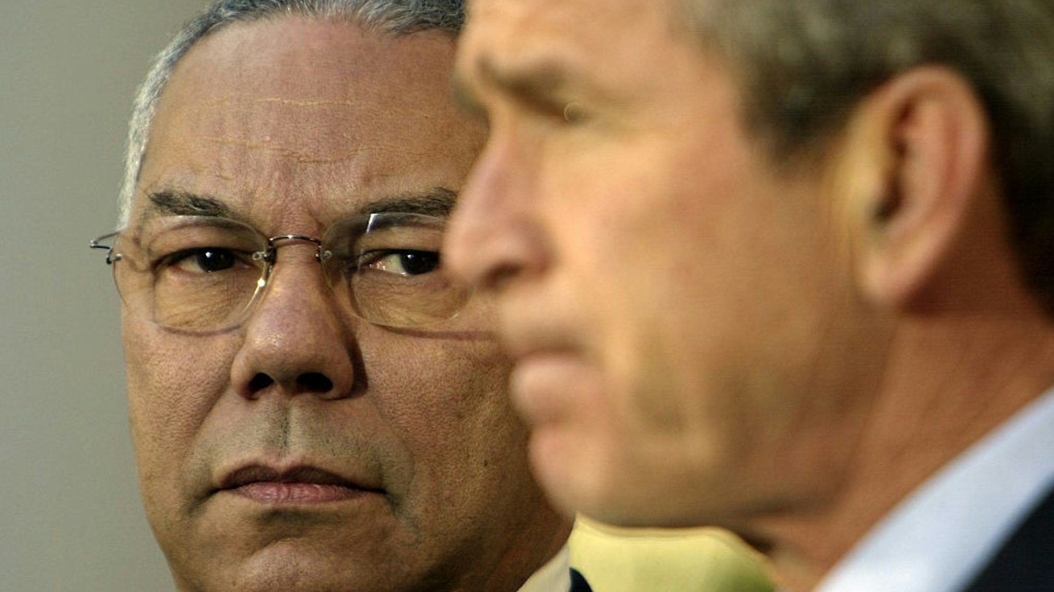 Secretary of State Colin Powell stands with President George W. Bush. (Photo by ��