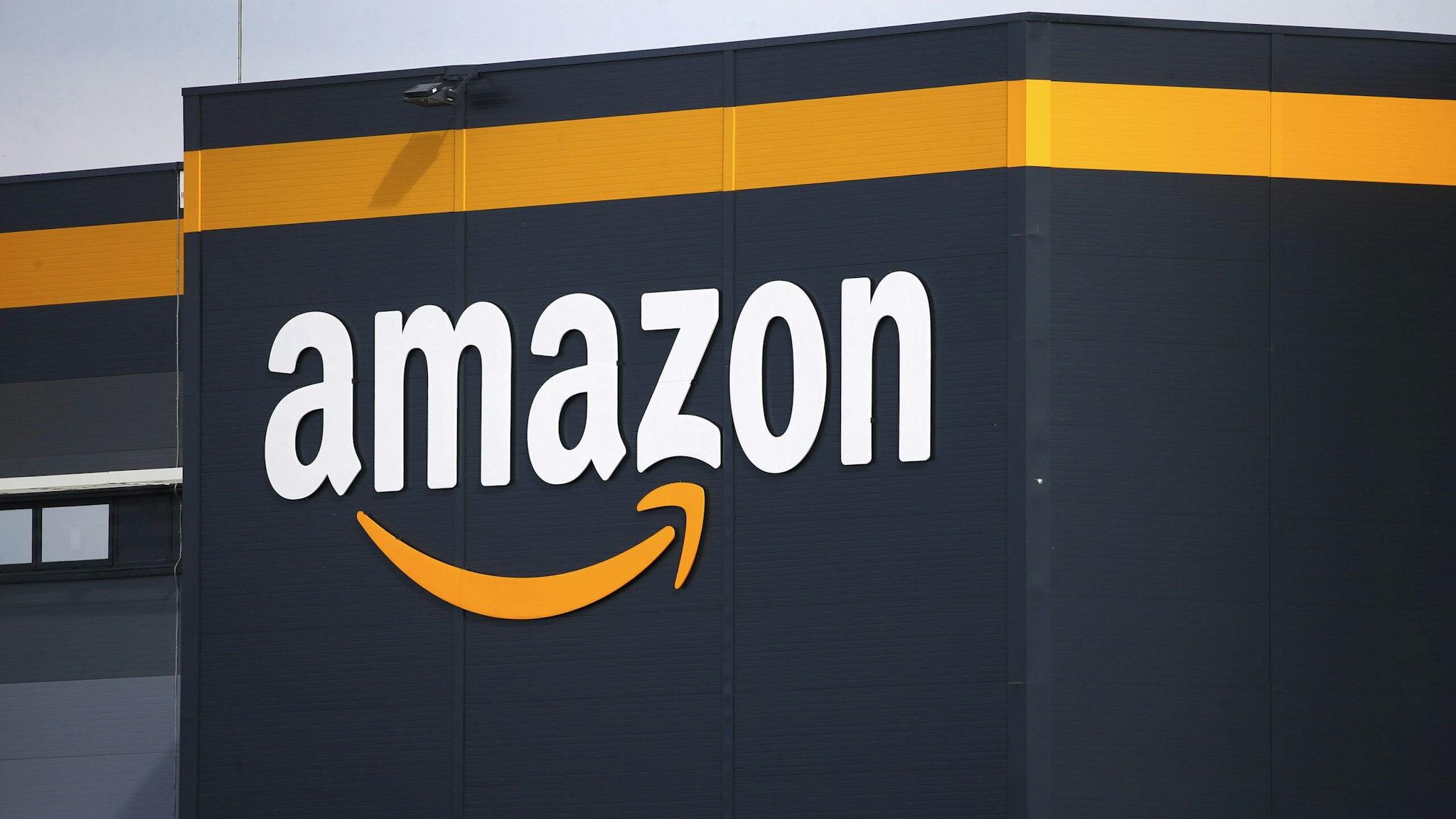 The logo of Amazon is seen on the facade of the company logistics center on April 21, 2020 in Bretigny-sur-Orge, France. The French government has ordered the American e-commerce giant Amazon to take measures at four of its sites in France to better protect employees against Covid-19. This Tuesday, the Versailles Court of Appeal examined the appeal filed by Amazon against a decision requiring it to restrict its activity in France during this period of confinement. Amazon Logistique France has finally decided to close all of its warehouses pending the decision of the Versailles Court of Appeal, which will be made on Friday April 24.
