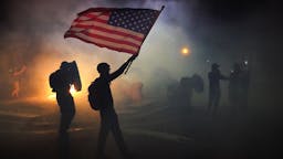 American Flag Protest A protester flies an American flag while walking through tear gas fired by federal officers during a protest in front of the Mark O. Hatfield U.S. Courthouse on July 21, 2020 in Portland, Oregon. The federal police response to the ongoing protests against racial inequality has been criticized by city and state elected officials. (Photo by Nathan Howard/Getty Images)
