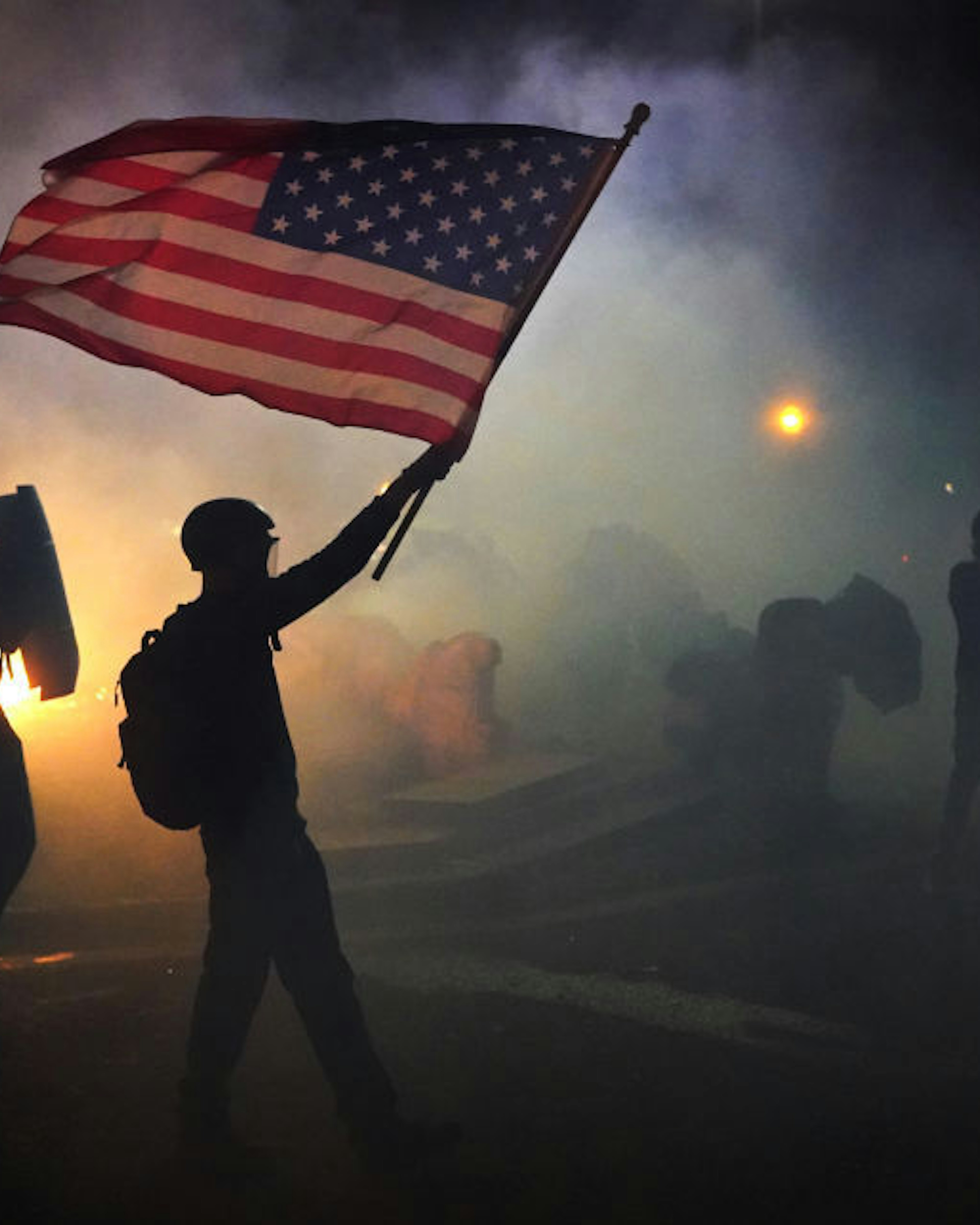 A protester flies an American flag while walking through tear gas fired by federal officers during a protest in front of the Mark O. Hatfield U.S. Courthouse on July 21, 2020 in Portland, Oregon. The federal police response to the ongoing protests against racial inequality has been criticized by city and state elected officials. (Photo by Nathan Howard/Getty Images)