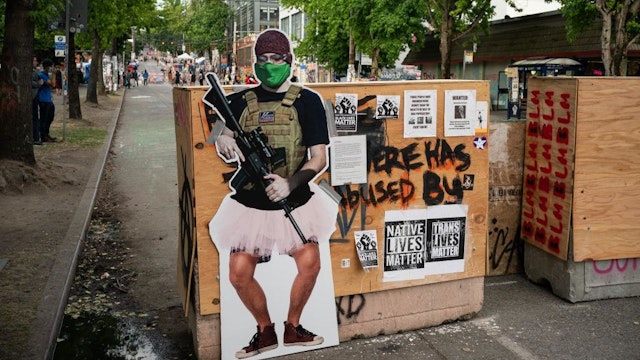A cutout image of a man holding a firearm, called ANTI-FAiry and created by activists to critique the recent manipulation and misleading use of the mans image by Fox News, is seen at an entrance in the area known as the Capitol Hill Organized Protest (CHOP) on June 24, 2020 in Seattle, Washington. On Monday, Seattle Mayor Jenny Durkan said that the city would phase down the CHOP zone and that the Seattle Police Department would return to its vacated East Precinct. (Photo by David Ryder/Getty Images)