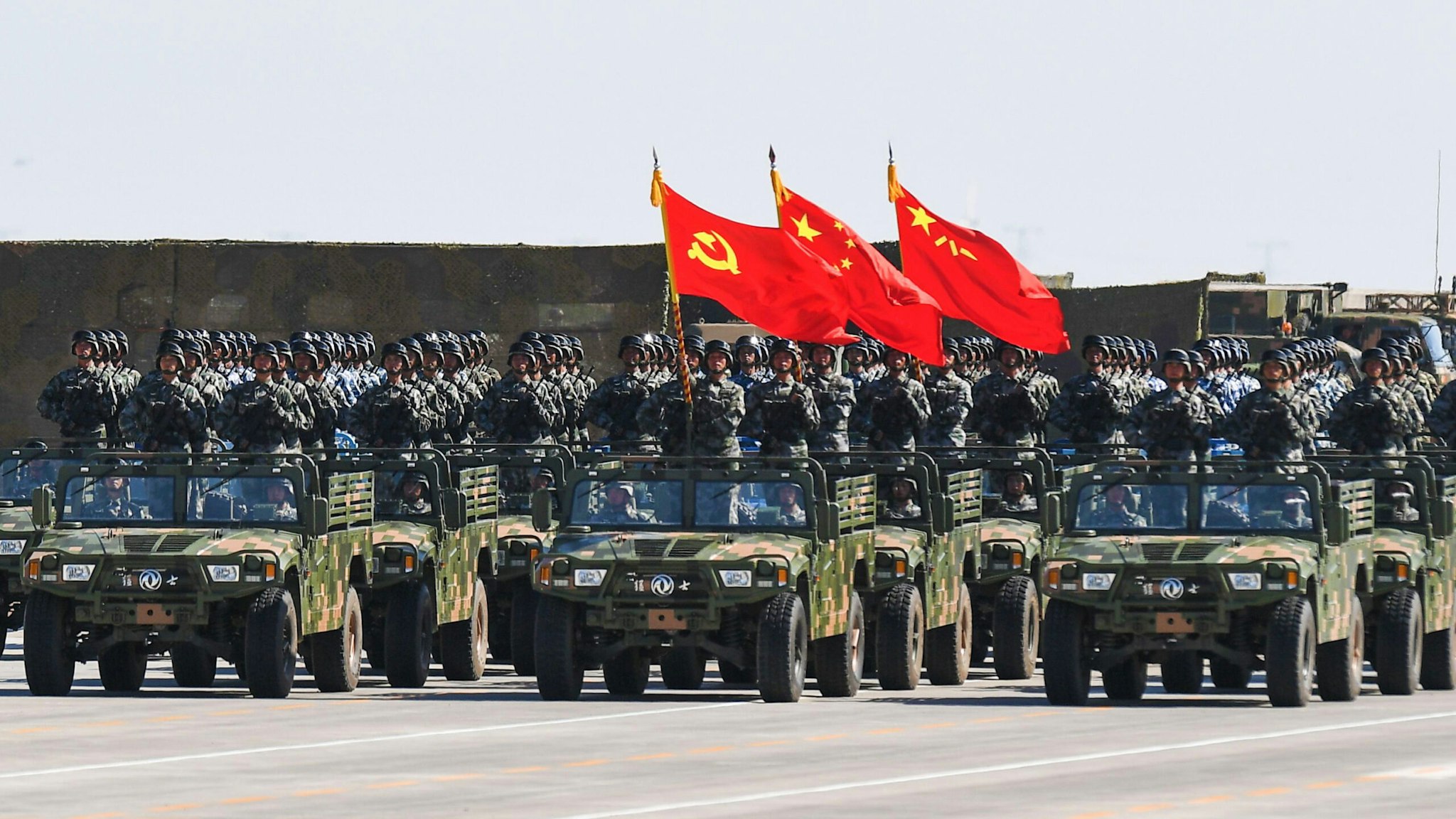 Chinese soldiers carry the flags of (L to R) the Communist Party, the state, and the People's Liberation Army during a military parade at the Zhurihe training base in China's northern Inner Mongolia region on July 30, 2017. China held a parade of its armed forces on July 30 to mark the 90th anniversary of the People's Liberation Army (PLA) in a display of military might.