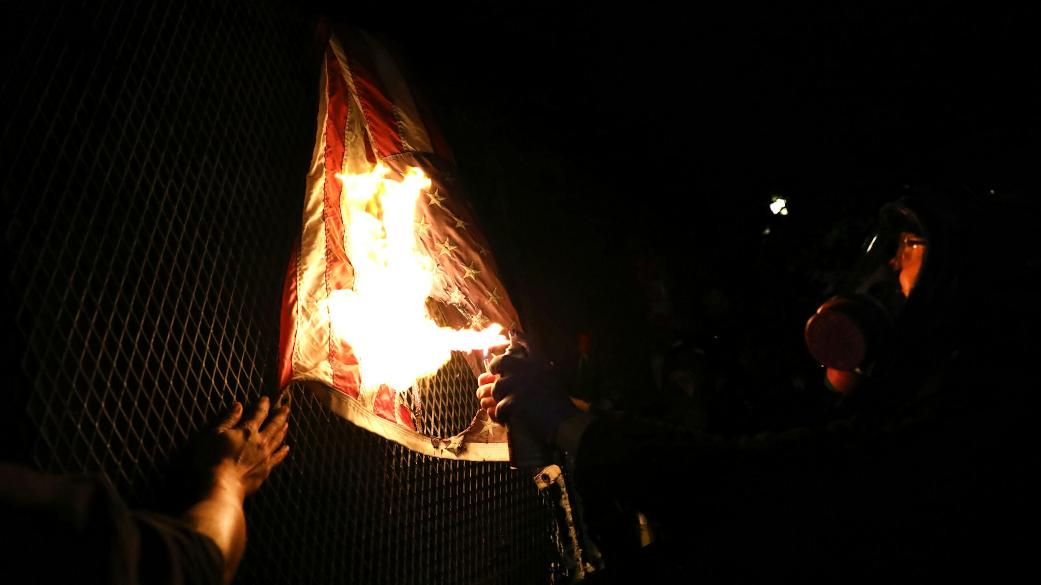 PORTLAND, OREGON - JULY 25: An American Flag is burned as protesters gather in front of the Mark O. Hatfield federal courthouse in downtown Portland as the city experiences another night of unrest on July 25, 2020 in Portland, Oregon. For over 55 straight nights, protesters in downtown Portland have faced off in often violent clashes with the Portland Police Bureau and, more recently, federal officers. The demonstrations began to honor the life of George Floyd and other black Americans killed by law enforcement and have intensified as the Trump administration called in the federal officers.