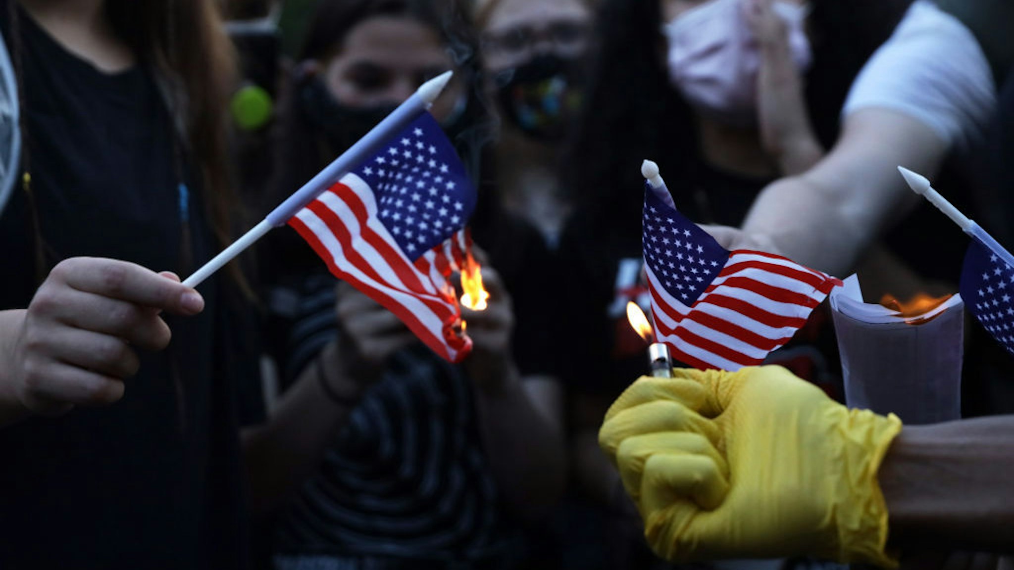 Anti-Trump activists burn U.S. flags at Black Lives Matter Plaza near the White House July 4, 2020 in Washington, DC. Anti-Trump activists rallied on Independence Day to voice their disapproval of President Trump's handling in the wake of the death of George Floyd. (Photo by Alex Wong/Getty Images)