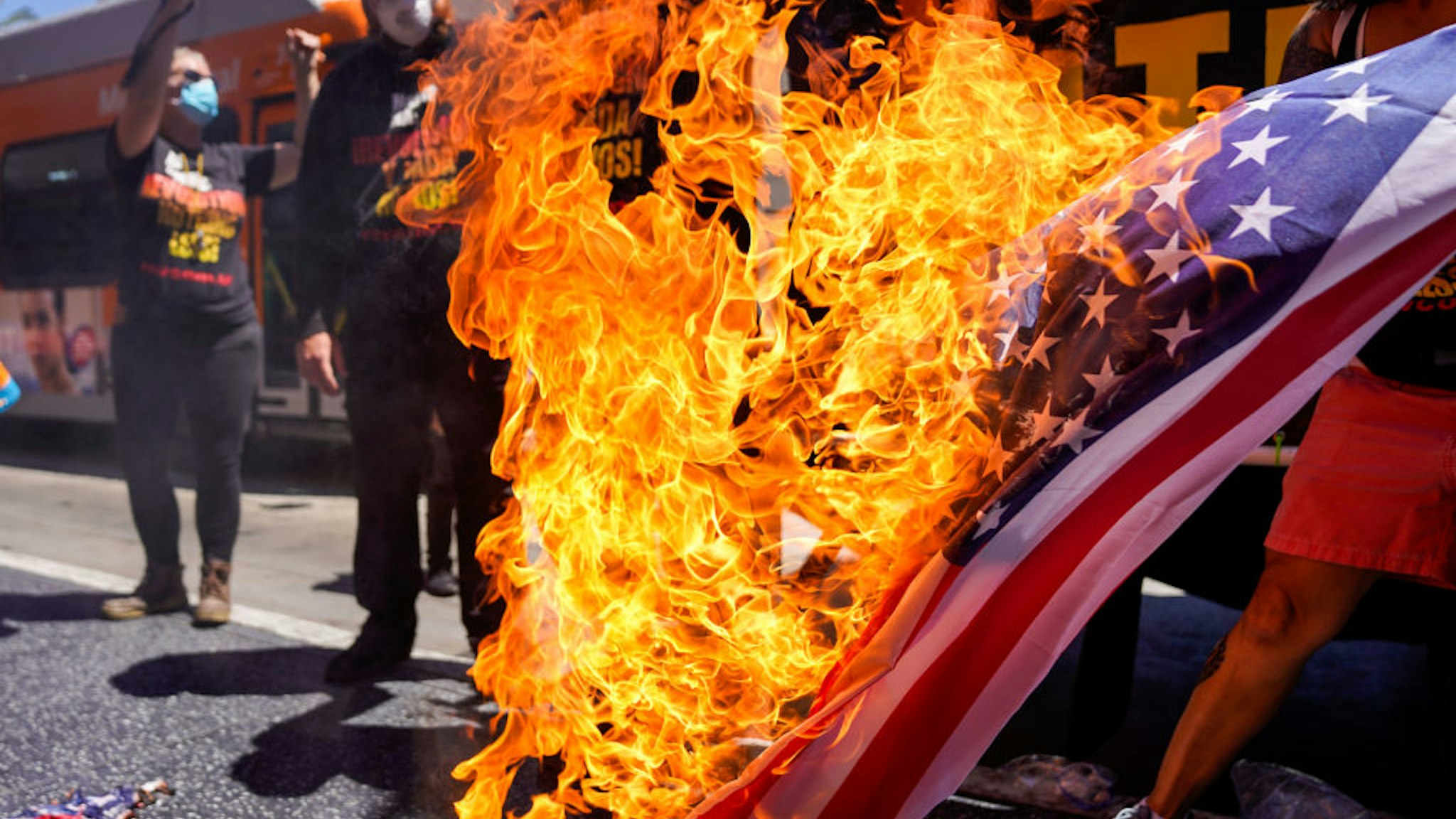 Protesters set fire to an American flag near President Donald Trumps Star on the Hollywood Walk of Fame, part of the Demonstrate How to Dishonor the American Flag event put on by the Revolution Club in Los Angeles on Saturday, July 4, 2020 in Los Angeles, CA. The event was led by Activist Gregory `Joey' Johnson will burn the U.S. flag to protest President Donald Trump's call to re-criminalize flag burning. (Kent Nishimura / Los Angeles Times via Getty Images)