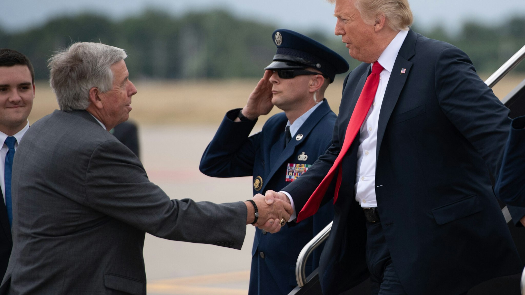 US President Donald Trump shakes hands with Missouri Governor Mike Parson (L) as he disembarks from Air Force One upon arrival at St. Louis Lambert International Airport in St. Louis, Missouri, July 26, 2018, as he travels to nearby Granite City, Illinois to speak about the economy. (Photo by SAUL LOEB / AFP) (Photo credit should read SAUL LOEB/AFP via Getty Images)