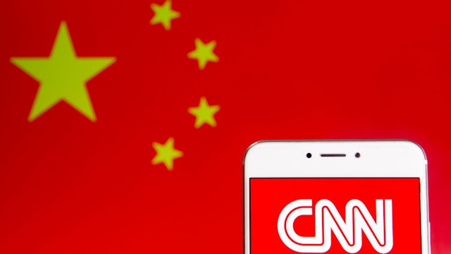 In this photo illustration the American news-based pay television channel CNN logo is seen on an Android mobile device with People's Republic of China flag in the background.