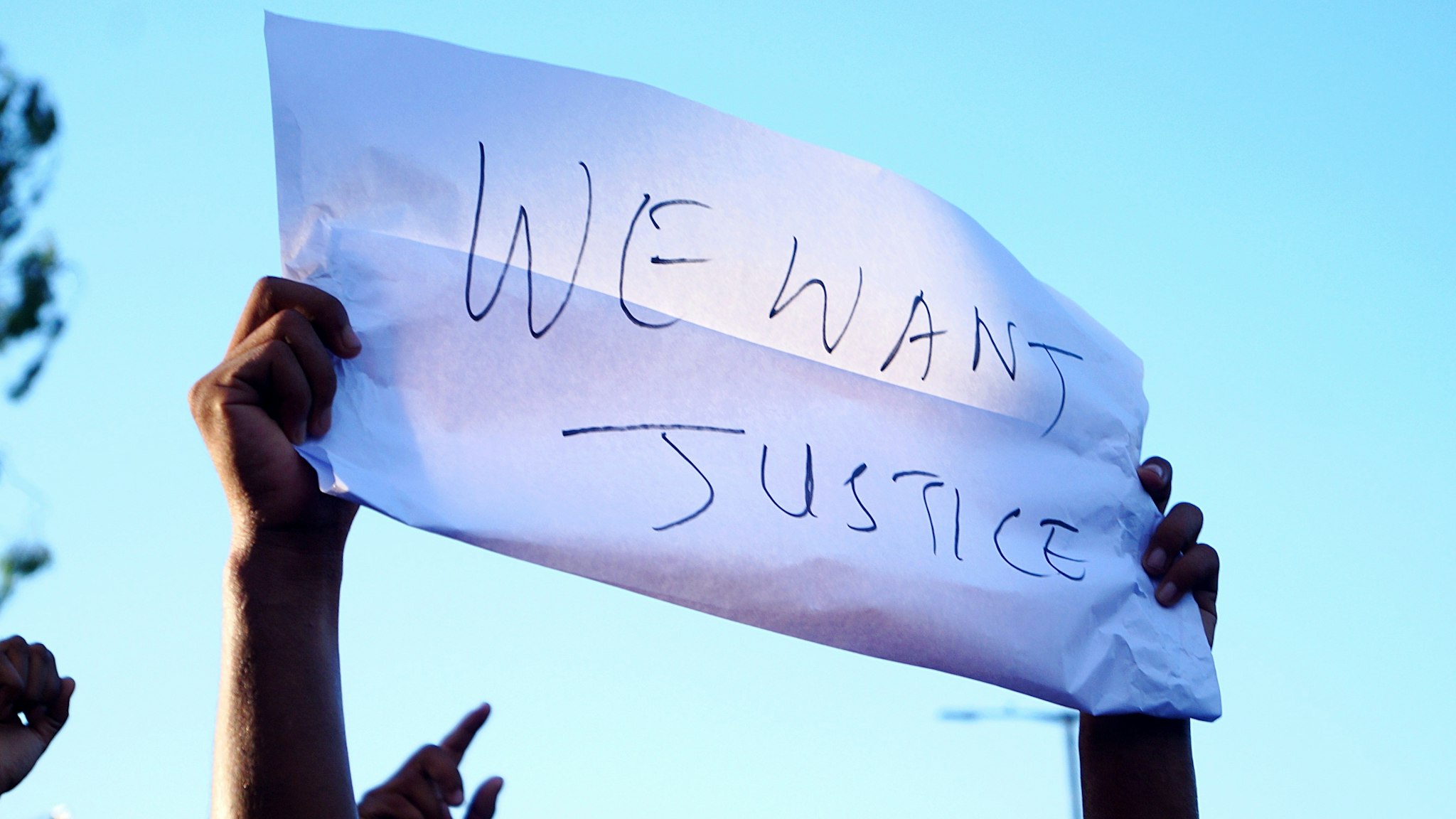 Low Angle View Of Person Holding Paper With Justice Text Against Sky - stock photo