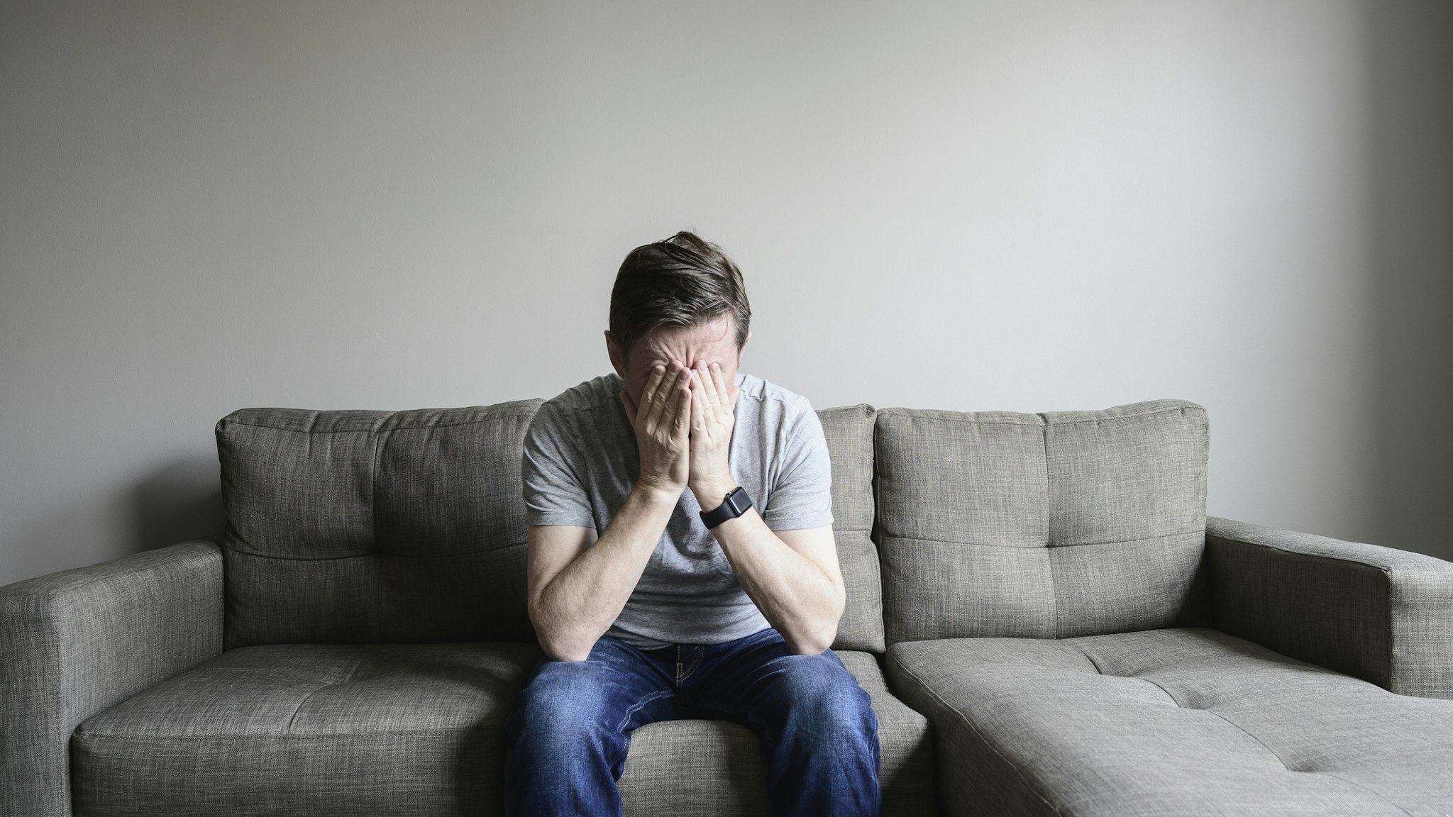 Depressed mature man sitting on couch - stock photo