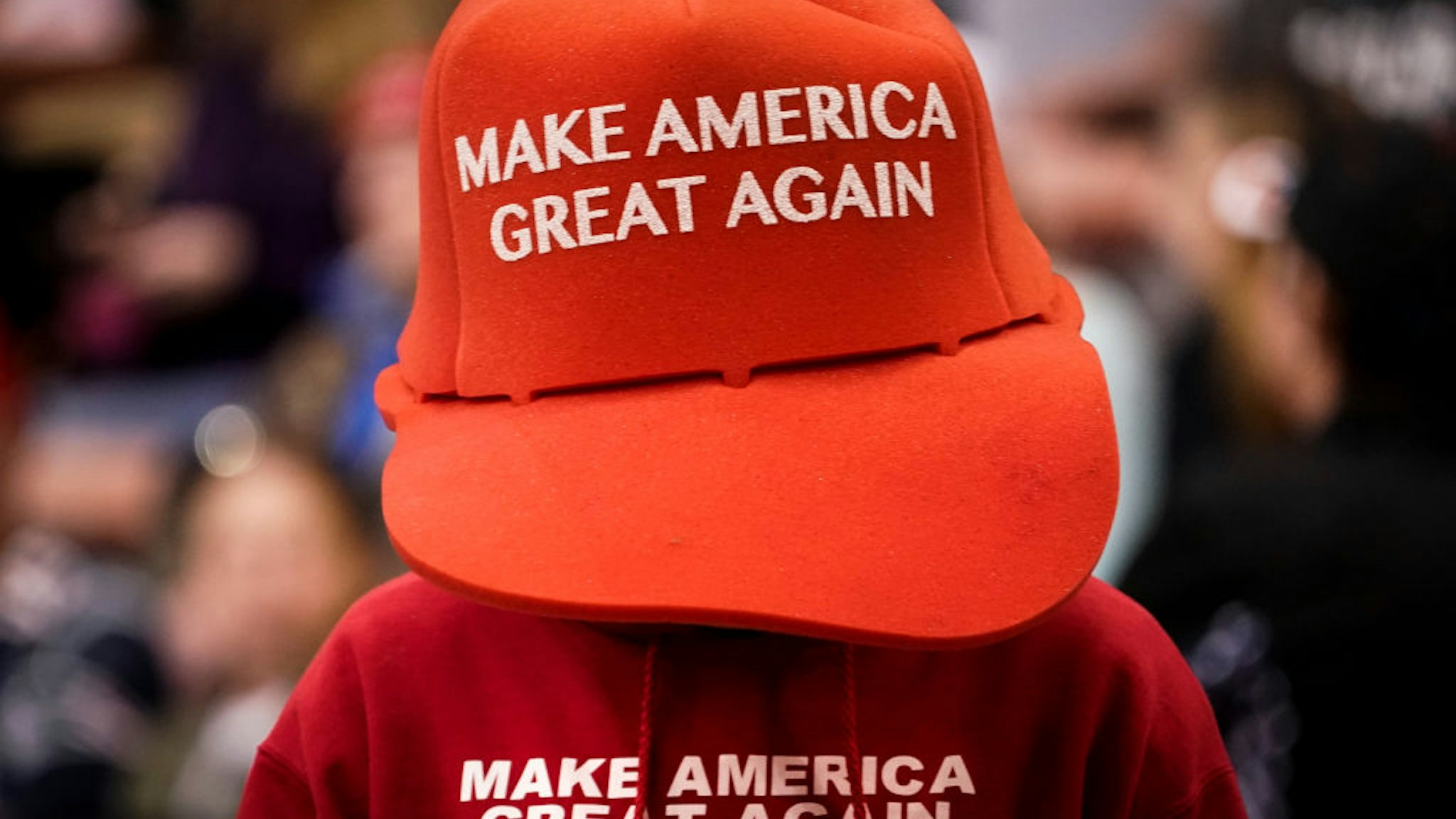 A supporter of U.S. President Donald Trump wears an oversize "Make America Great Again Hat" as he waits for the start of a "Keep America Great" rally at Southern New Hampshire University Arena on February 10, 2020 in Manchester, New Hampshire.