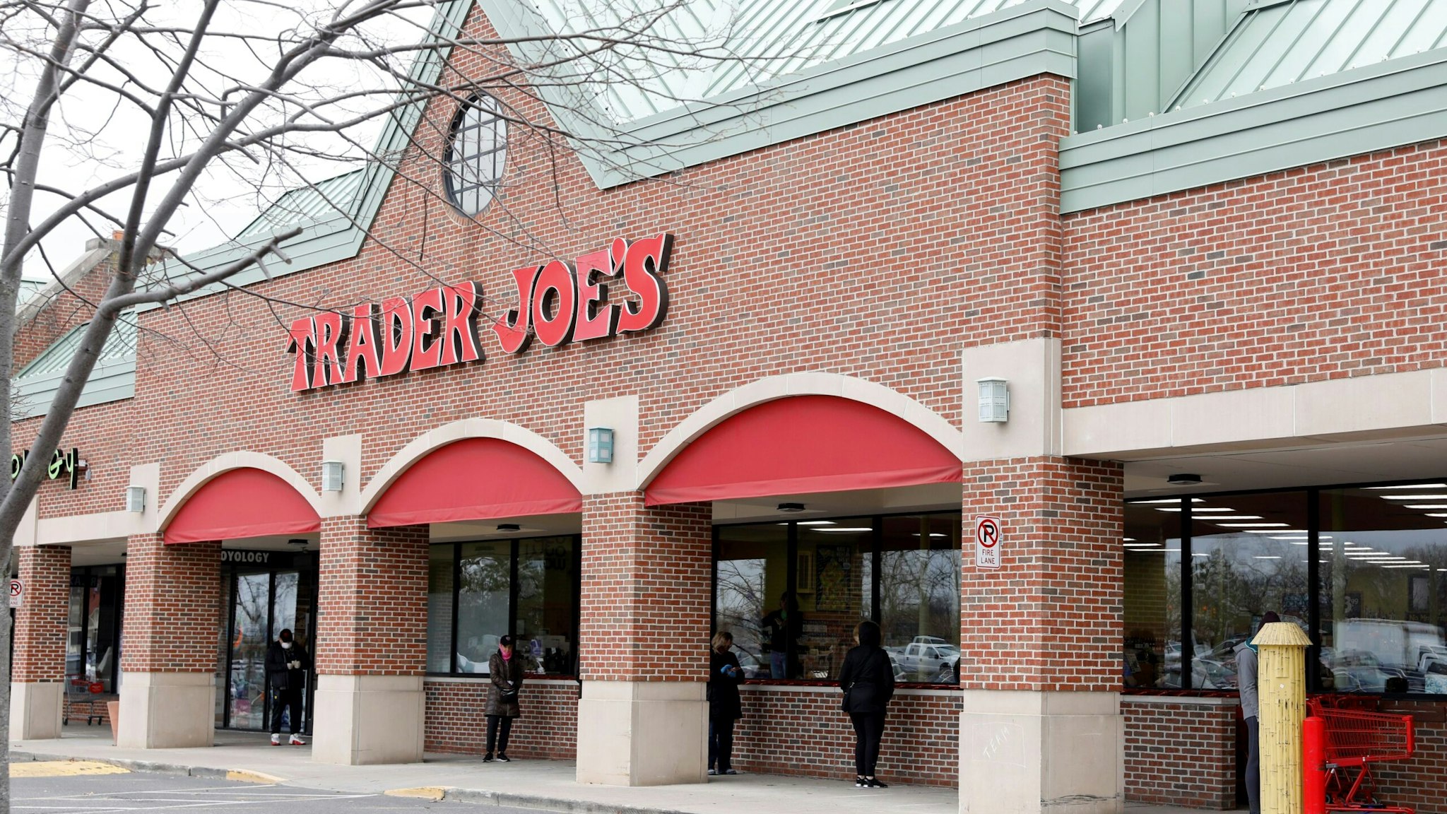 People social distance as they wait to get into the Trader Joe's store to avoid the spread of COVID-19 in Bloomfield Hills Michigan on March 30, 2020. - Trader Joe's only lets 20 customers in the store at a time to shop. (Photo by JEFF KOWALSKY / AFP) (Photo by JEFF KOWALSKY/AFP via Getty Images)