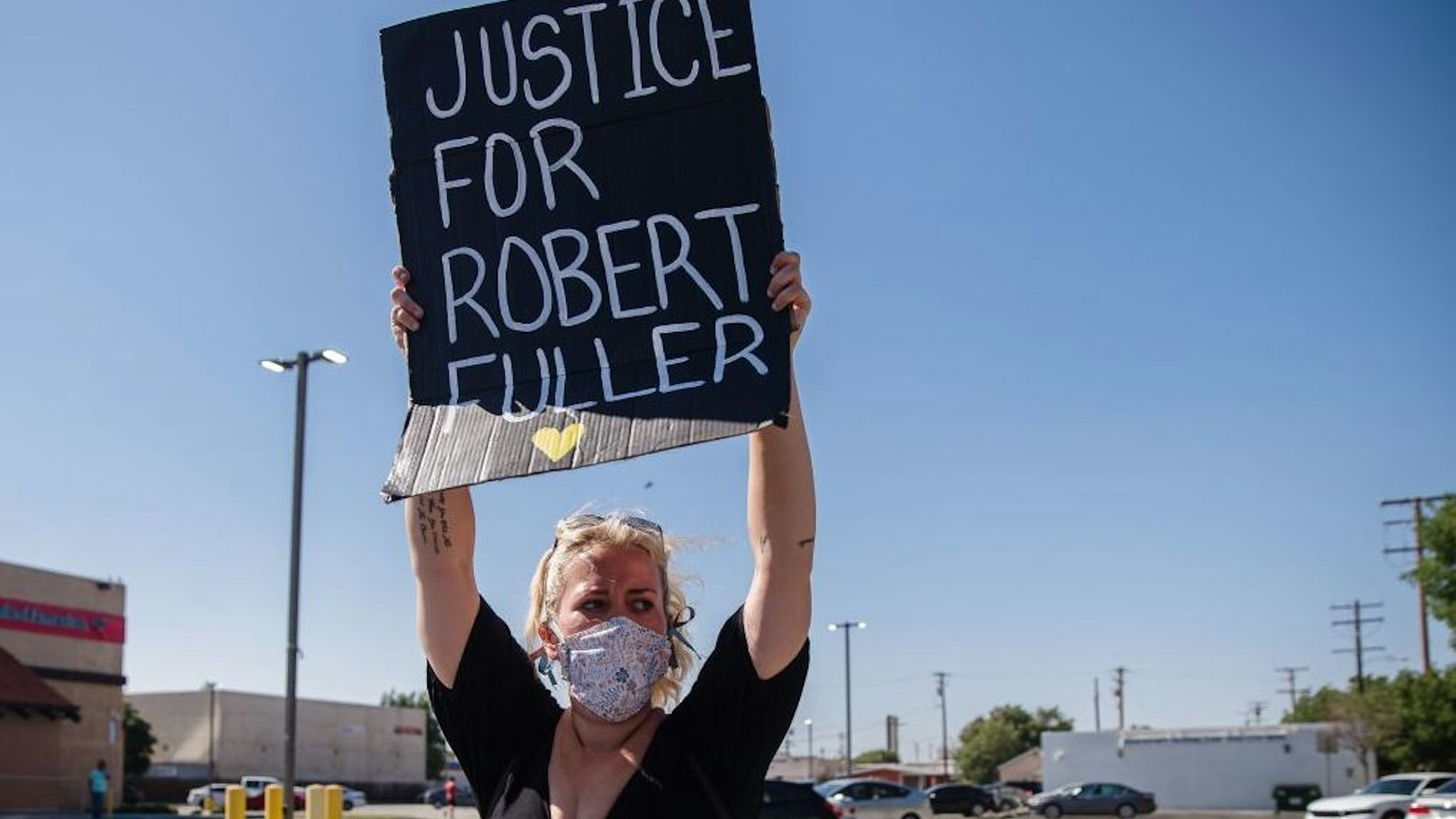 A protester holds up a placard on Palmdale Blvd as people gather to demand justice for Robert Fuller, a young black man who was found hanging from a tree, on June 16, 2020, in Palmdale, California.