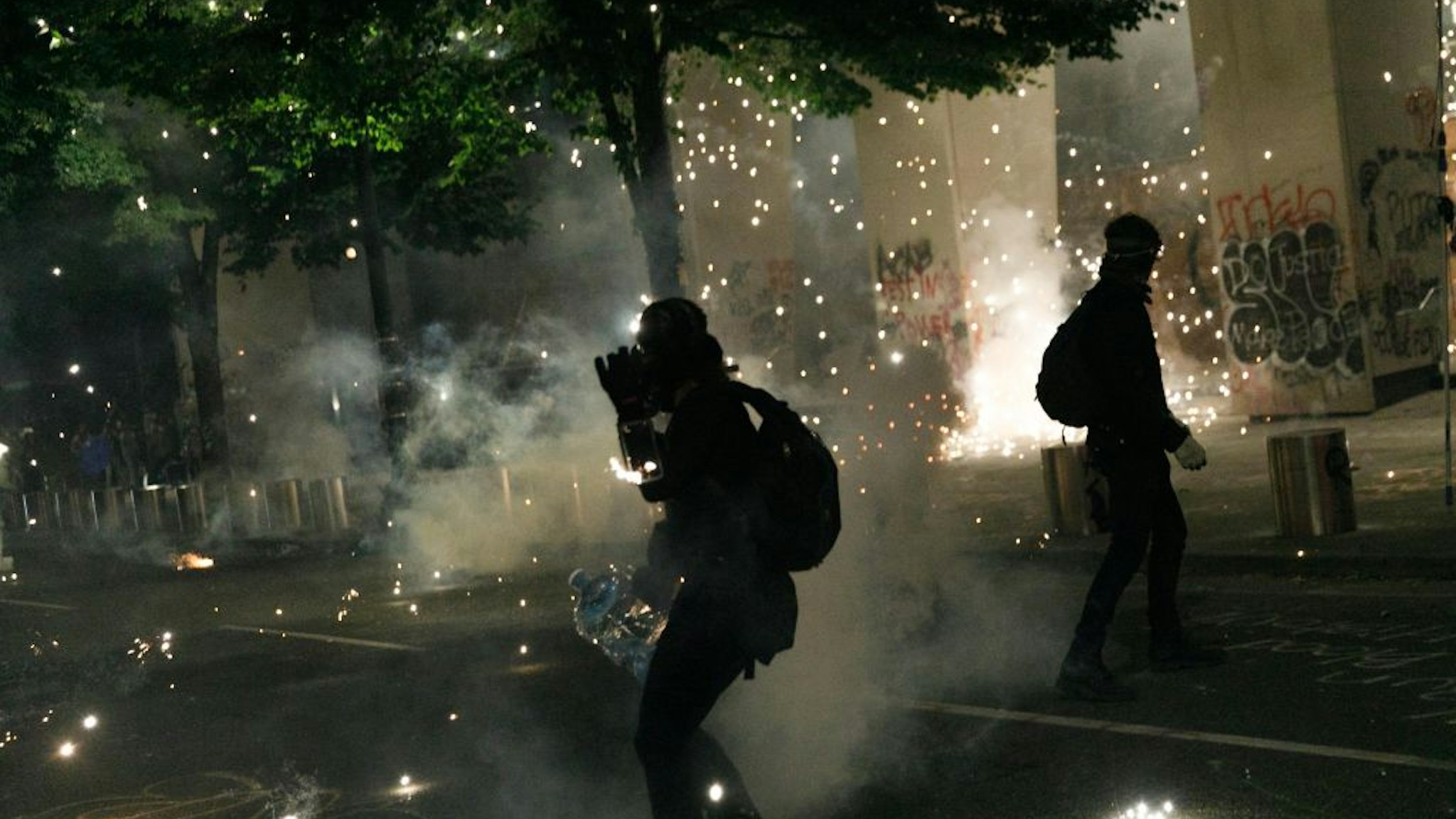 Tear gas and fireworks mix as Black Lives Matter supporters demonstrate in Portland, Oregon on July 4, 2020 for the thirty-eighth day in a row at Portland's Justice Center and throughout Portland,