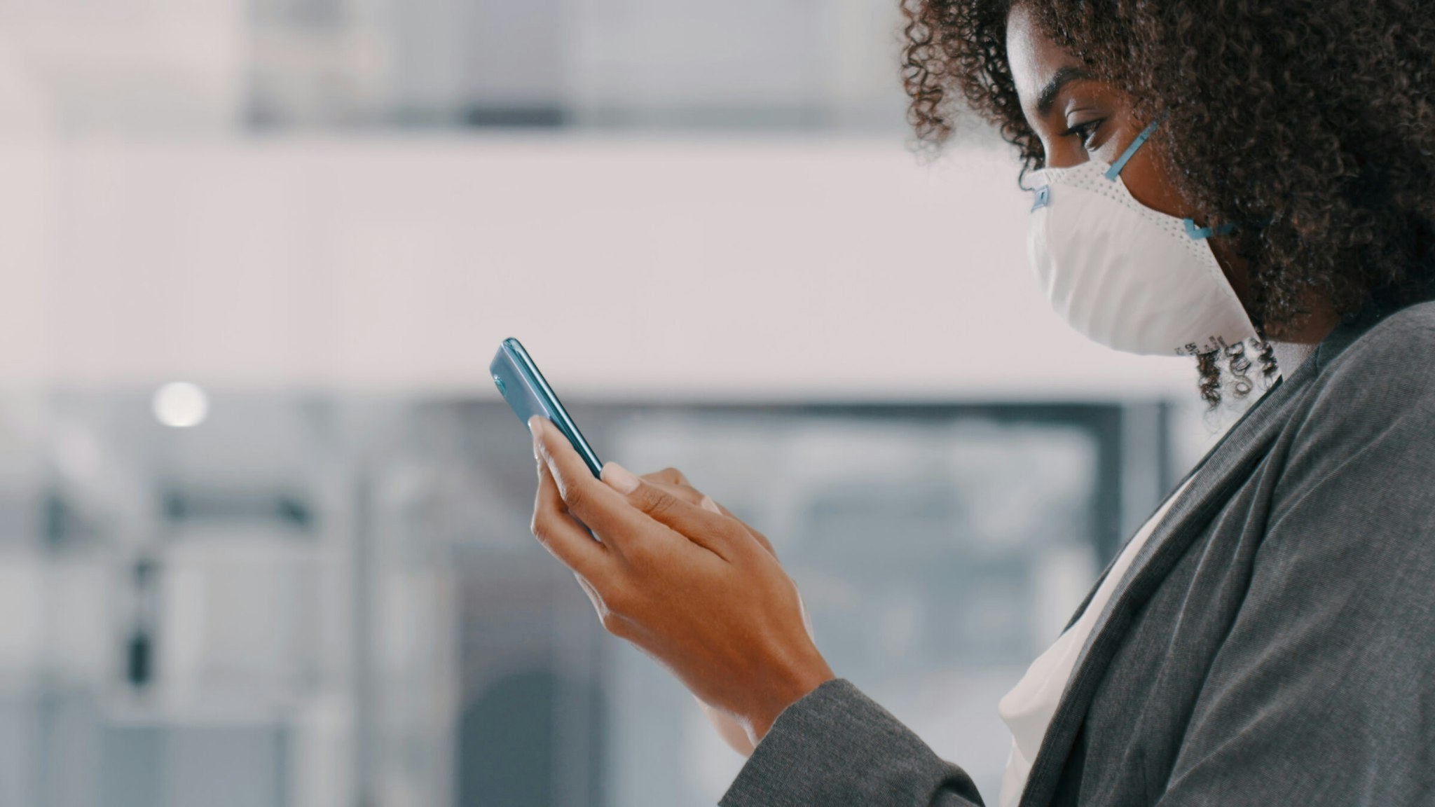 Shot of a young businesswoman wearing a mask and using a smartphone in a modern officeShot of a young businesswoman wearing a mask and using a smartphone in a modern office