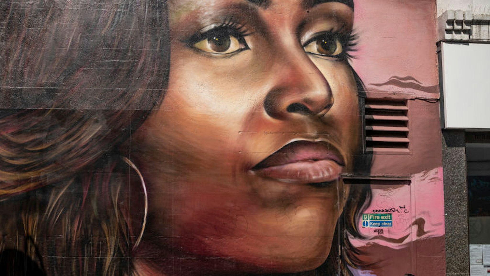 A girl scoots past a mural of Michelle Obama in Brixton on June 24, 2020 in London, England. Yesterday, the Prime Minister Boris Johnson announced the reopening of restaurants, pubs, hairdressers and hotels on July 04 and the introduction of a ‚Äúone metre plus‚Äù social distancing rule. (Photo by Dan Kitwood/Getty Images)