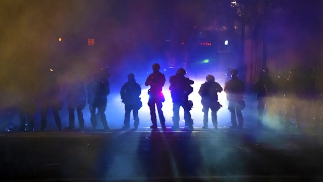 PORTLAND, OR - JULY 21: Federal officers walk through tear gas while dispersing a crowd of about a thousand people during a protest at Mark O. Hatfield U.S. Courthouse on July 21, 2020 in Portland, Oregon. State and city elected officials have called for the federal officers to leave Portland as clashes between protesters and federal police continue to escalate.