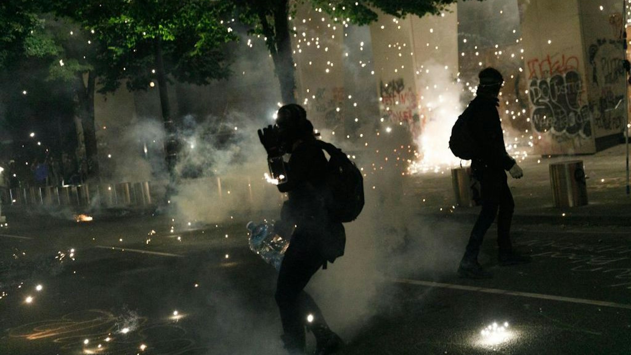 Tear gas and fireworks mix as Black Lives Matter supporters demonstrate in Portland, Oregon on July 4, 2020 for the thirty-eighth day in a row at Portland's Justice Center and throughout Portland, with a riot declared about 12.20 am on July 5. CS tear gas and less-lethal weapons were used, and multiple arrests were made. (Photo by John Rudoff/Anadolu Agency via Getty Images)