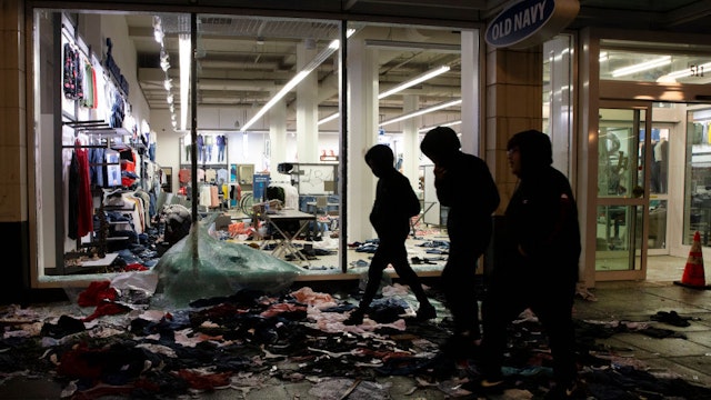 People walk past a store thats been looted during a riot following a peaceful rally expressing outrage over the death of George Floyd on May 30, 2020 in Seattle, Washington. Protests have erupted nationwide after Floyd died while in the custody of police in Minneapolis. (Photo by Karen Ducey/Getty Images)