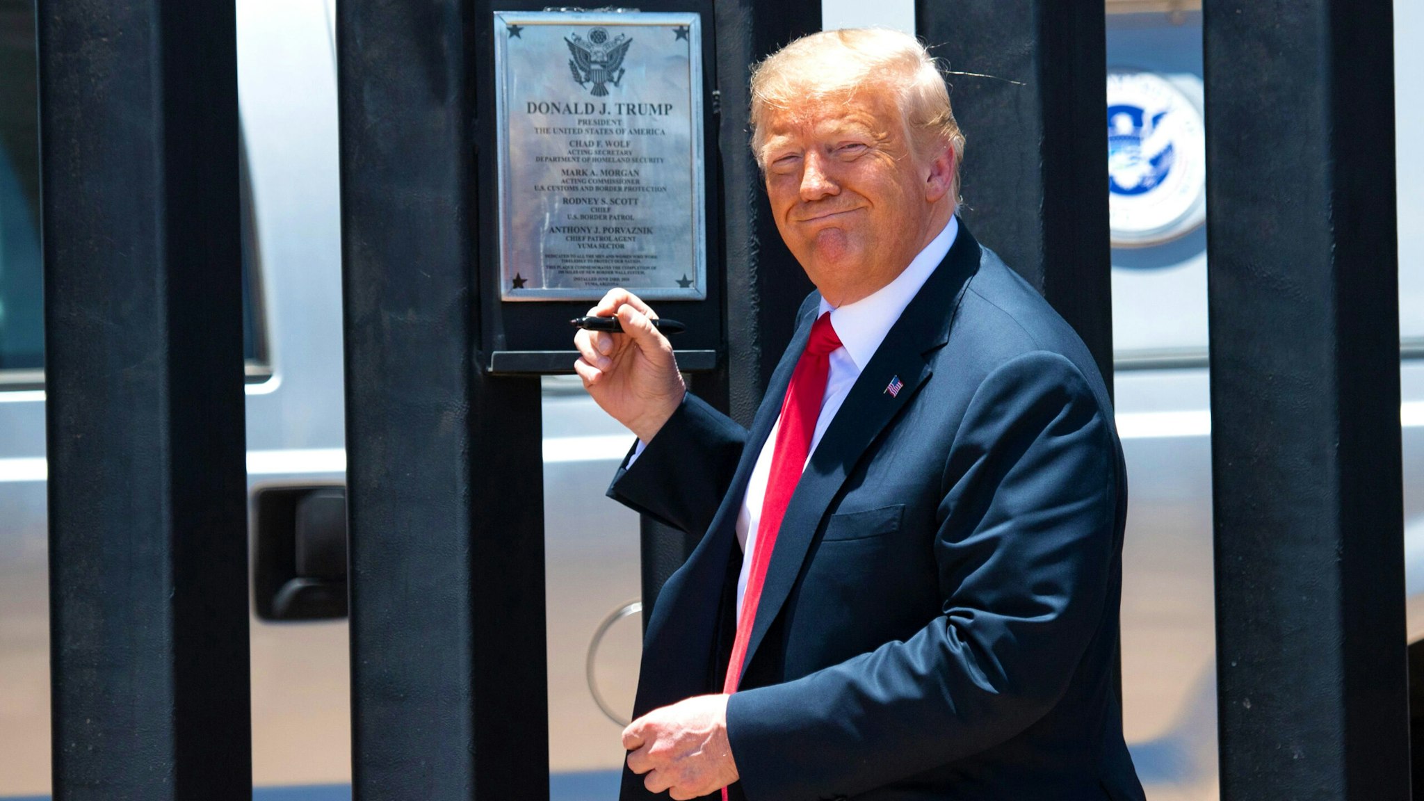 US President Donald Trump signs a plaque as he participates in a ceremony commemorating the 200th mile of border wall at the international border with Mexico in San Luis, Arizona, June 23, 2020.