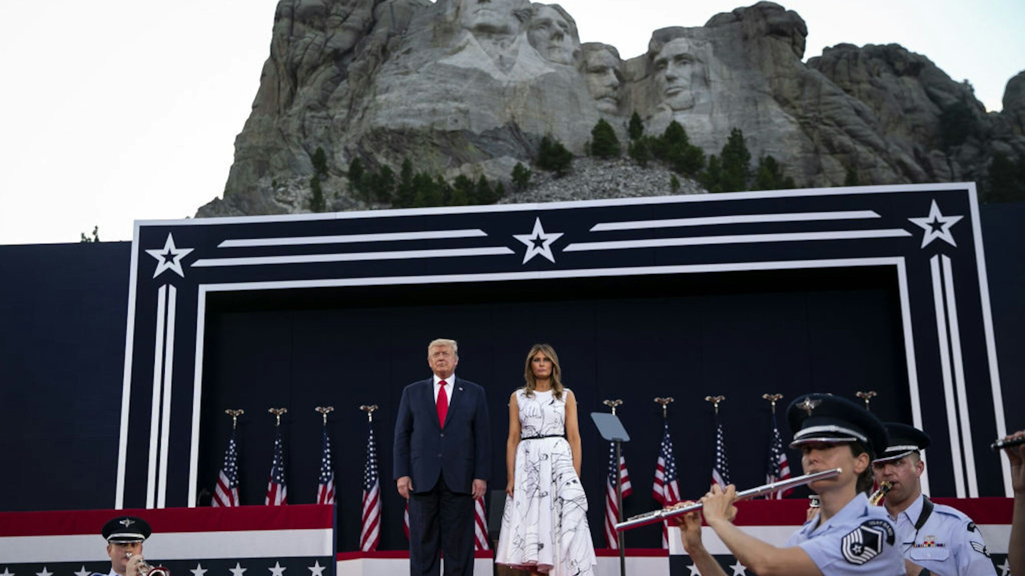 U.S. President Donald Trump, left, and First Lady Melania Trump attend an event at Mount Rushmore National Memorial in Keystone, South Dakota, U.S., on Friday, July 3, 2020. The early Independence Day celebration, which will feature a military flyover and the first fireworks in more than a decade, is expected to include about 7,500 ticketed guests who won't be required to wear masks or socially distance despite a spike in U.S. coronavirus cases.