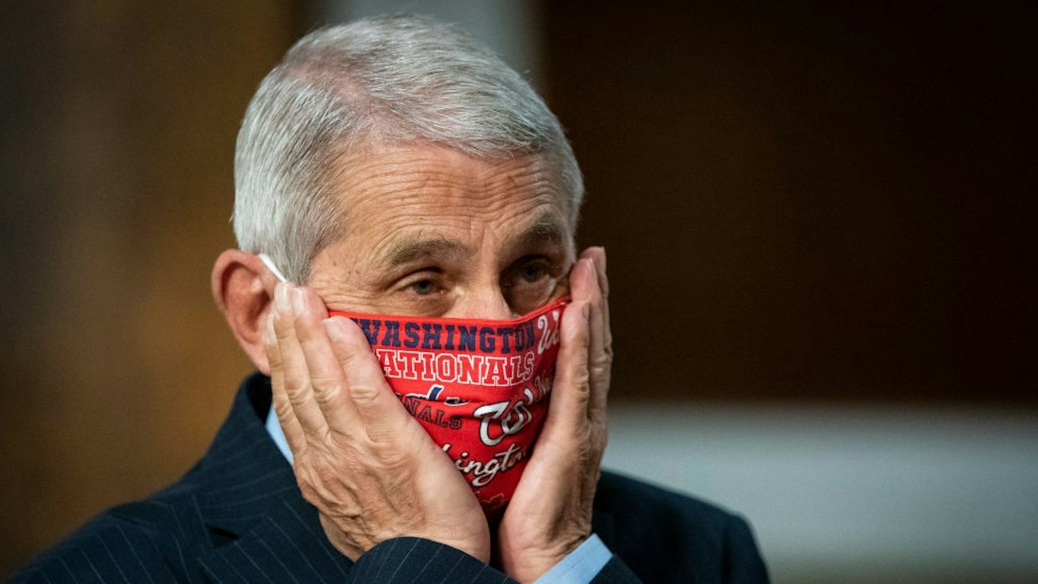 WASHINGTON, DC - JUNE 30: Anthony Fauci, director of the National Institute of Allergy and Infectious Diseases, adjusts a Washington Nationals protective mask while arriving to a Senate Health, Education, Labor and Pensions Committee hearing on June 30, 2020 in Washington, DC. Top federal health officials are expected to discuss efforts to get back to work and school during the coronavirus pandemic. (Photo by