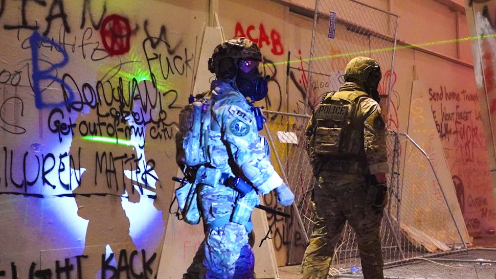 Feds Attempt To Intervene After Weeks Of Violent Protests In Portland PORTLAND, OR - JULY 20: Federal police walk toward the entrance of the Mark O. Hatfield U.S. Courthouse while a protester shines a laser in their direction on July 20, 2020 in Portland, Oregon. The federal police response to the ongoing protests against racial inequality has been criticized by city and state elected officials.