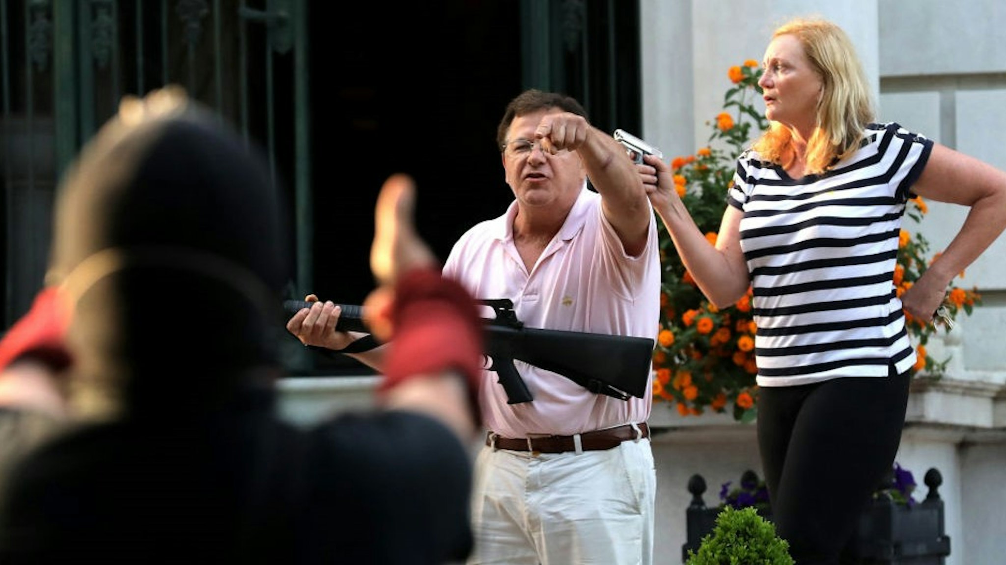 Armed homeowners standing in front of their house along Portland Place confront protesters as they march to Mayor Lyda Krewson's house on Sunday, June 28, 2020, in the Central West End in St. Louis. (