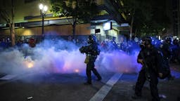 US-POLICE-PROTESTS Federal law enforcement throw tear gas at the crowd of demonstrators during a night of protest against racial injustice police brutality and the deployment of federal troops to US cities on July 29, 2020 in Portland, Oregon. - Protests in the US city of Portland have continued for more than 60 days. President Donald Trump's administration on July 29 agreed to a deal to defuse weeks of clashes with the withdrawal of federal forces whose presence enraged protesters, but the timing remained in dispute.