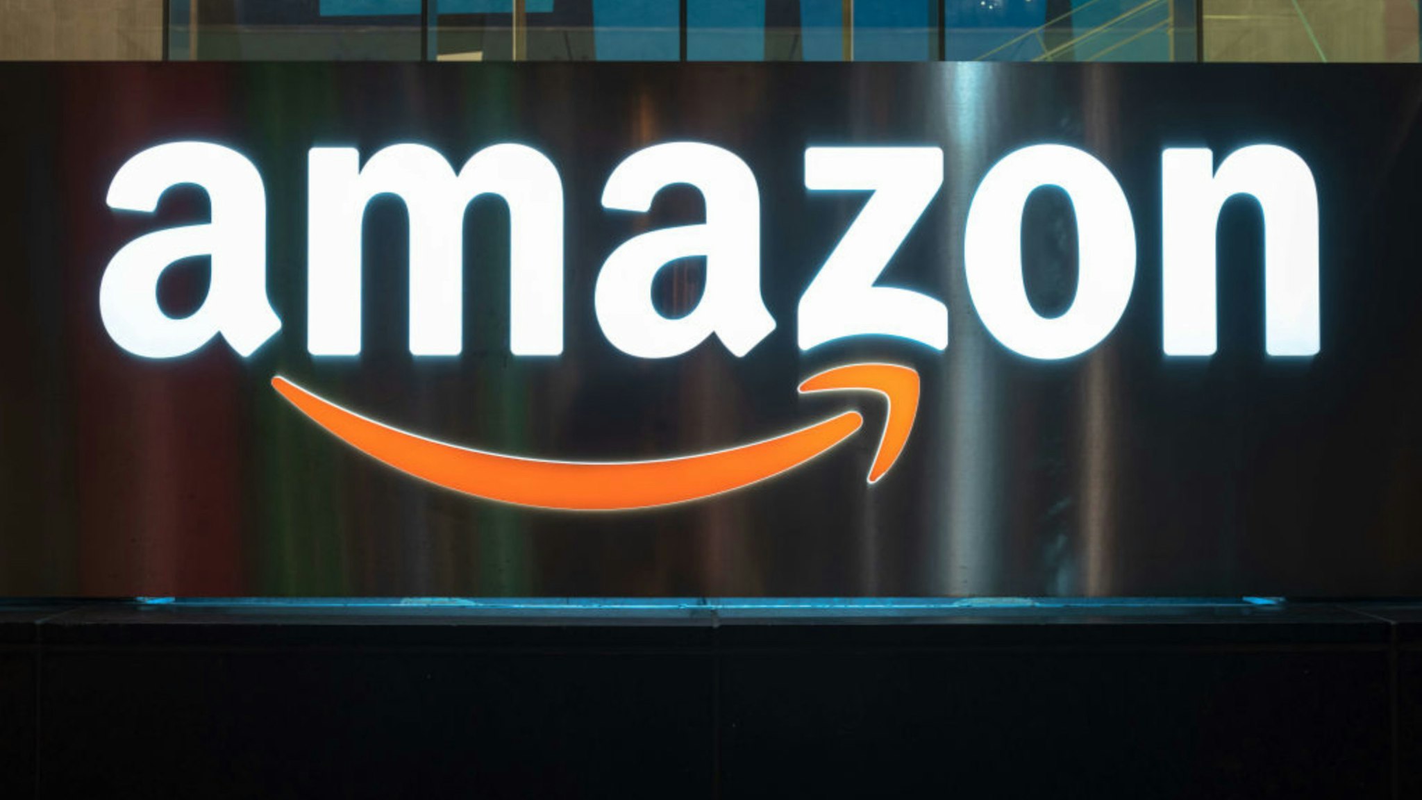 The Amazon logo illuminated at night. The sign can be seen in the downtown district of the Canadian city.