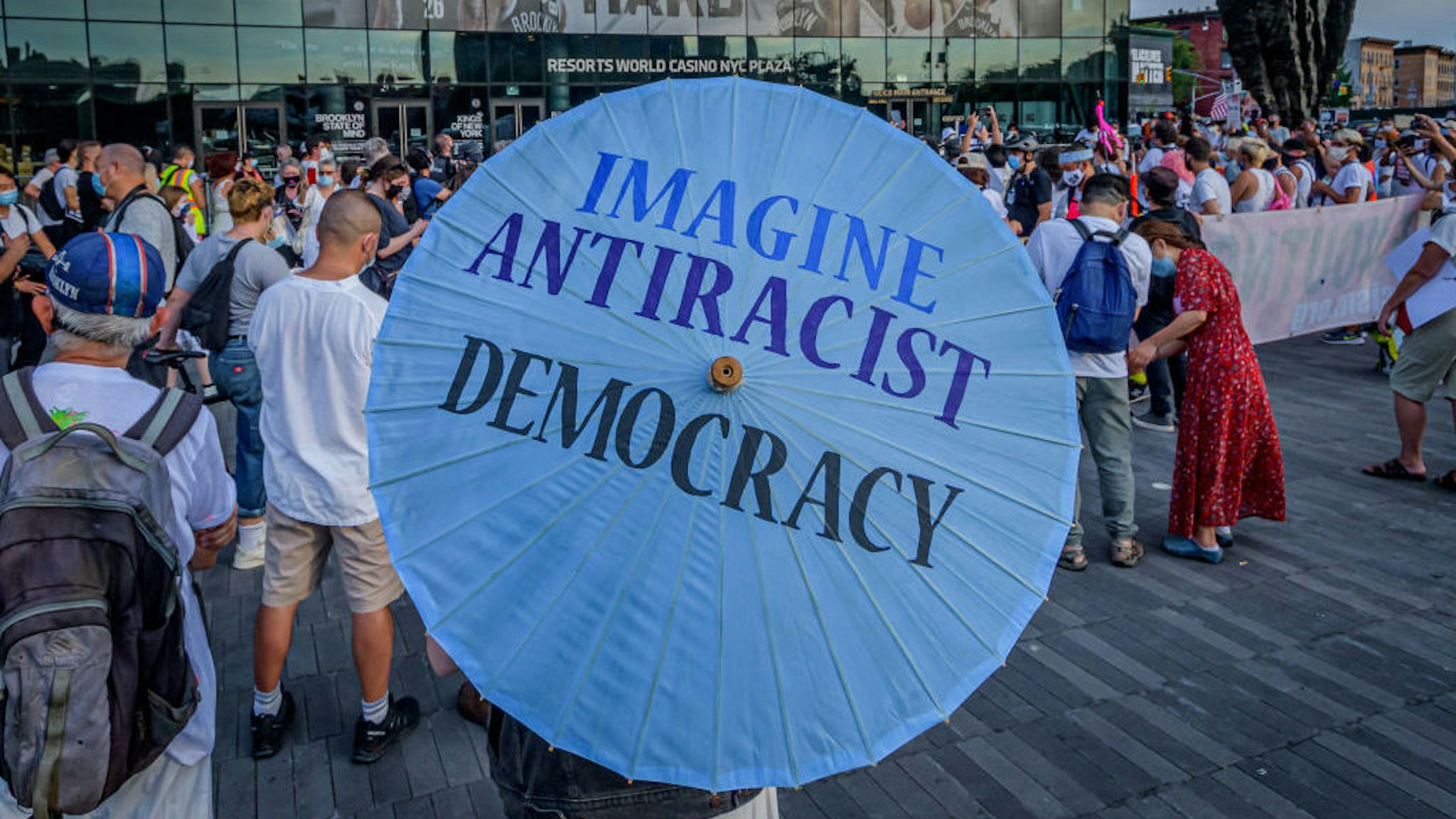 A participant carrying an umbrealla with the words Imagine Antiracist Democracy. On the eve of the Republican National Convention, a coalition of Americans reeling from the COVID-related deaths of loved ones, unemployment, and all this crisis has wrought gathered at Barclays Center to turn their sadness and frustration into protest by organizing the March for the Dead, Fight for the Living, a candlelit procession across the Brooklyn Bridge to the Trump Building at 40 Wall Street in Manhattan demanding the Trump administration and beyond to take responsible action to save lives and end suffering. (Photo by Erik McGregor/LightRocket via Getty Images)