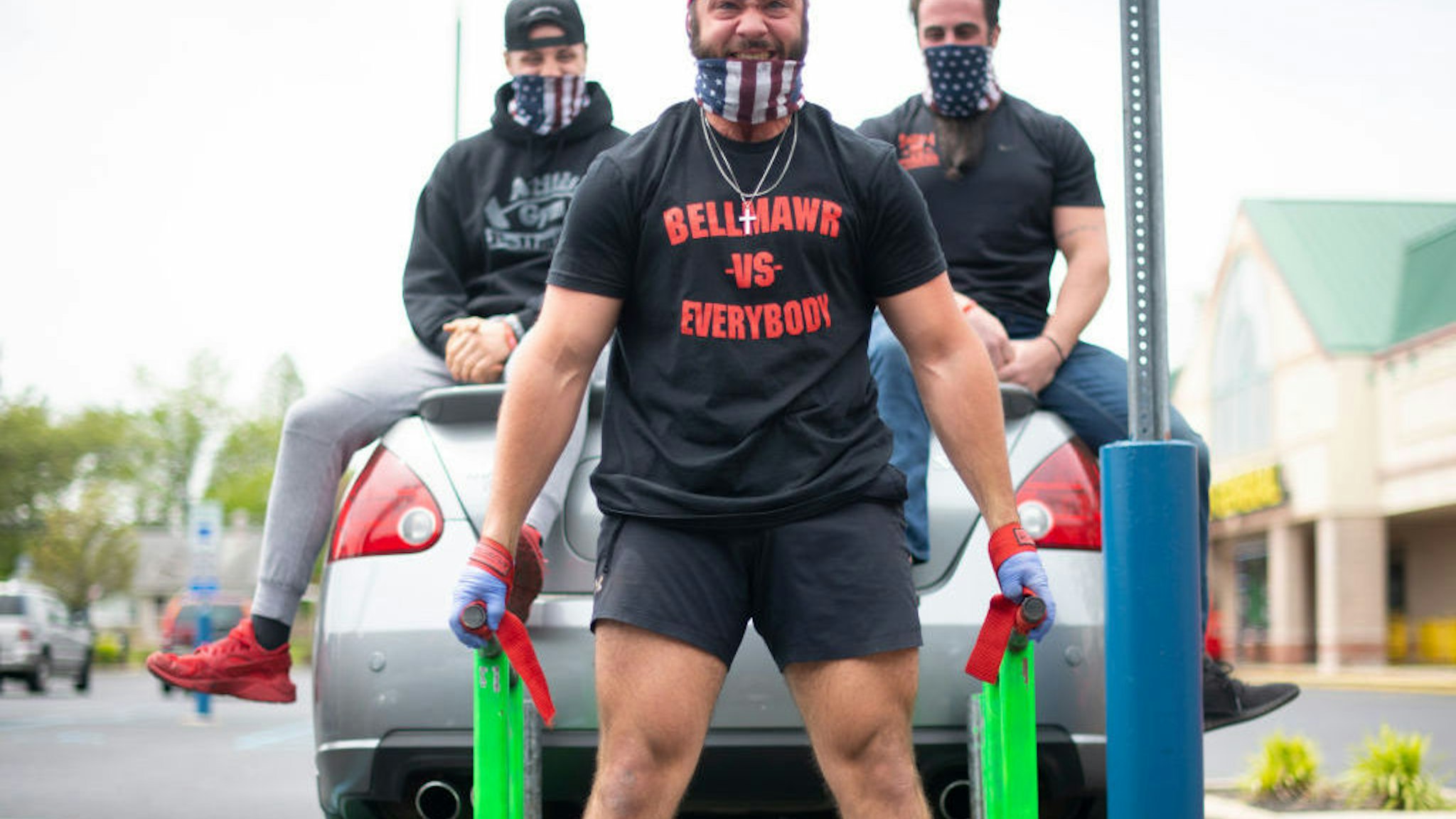 BELLMAWR, NJ - MAY 20: A body builder lifts a car and two men in the parking lot outside the Atilis Gym on May 20, 2020 in Bellmawr, New Jersey. The gym has opened for the third consecutive day, defying the New Jersey Governor's mandate that many retail businesses stay closed due to the coronavirus pandemic. (Photo by Mark Makela/Getty Images)