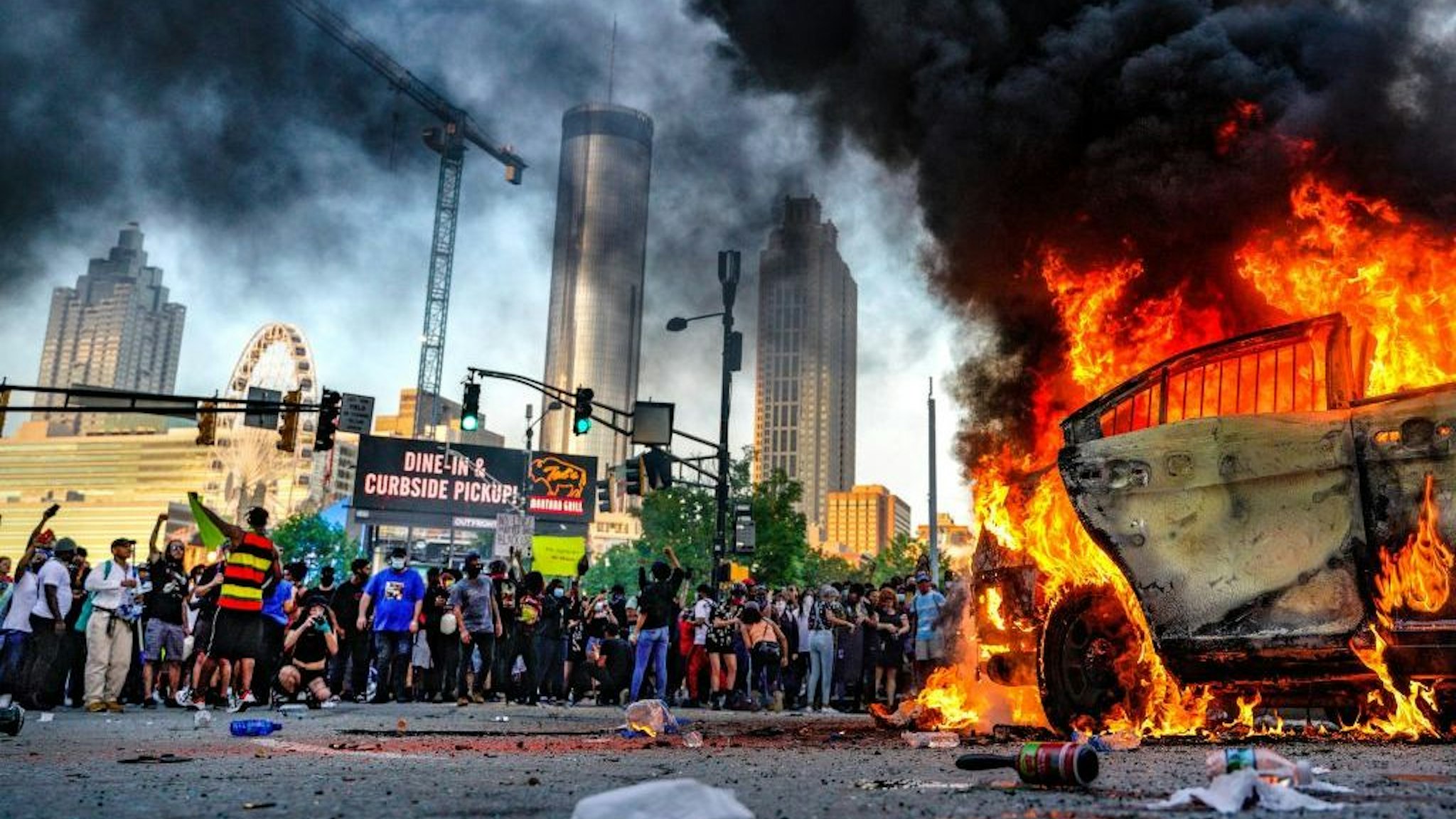 Protesters set a vehicle on fire during a protest following the death of George Floyd outside of the CNN Center next to Centennial Olympic Park in downtown Atlanta, Georgia, United States on May 29, 2020. It was announced Friday that Derek Chauvin, the former Minneapolis police officer caught on camera with his knee on Floyd√¢s neck, has been arrested and charged with third-degree murder and manslaughter. (Photo by Ben Hendren/Anadolu Agency via Getty Images)