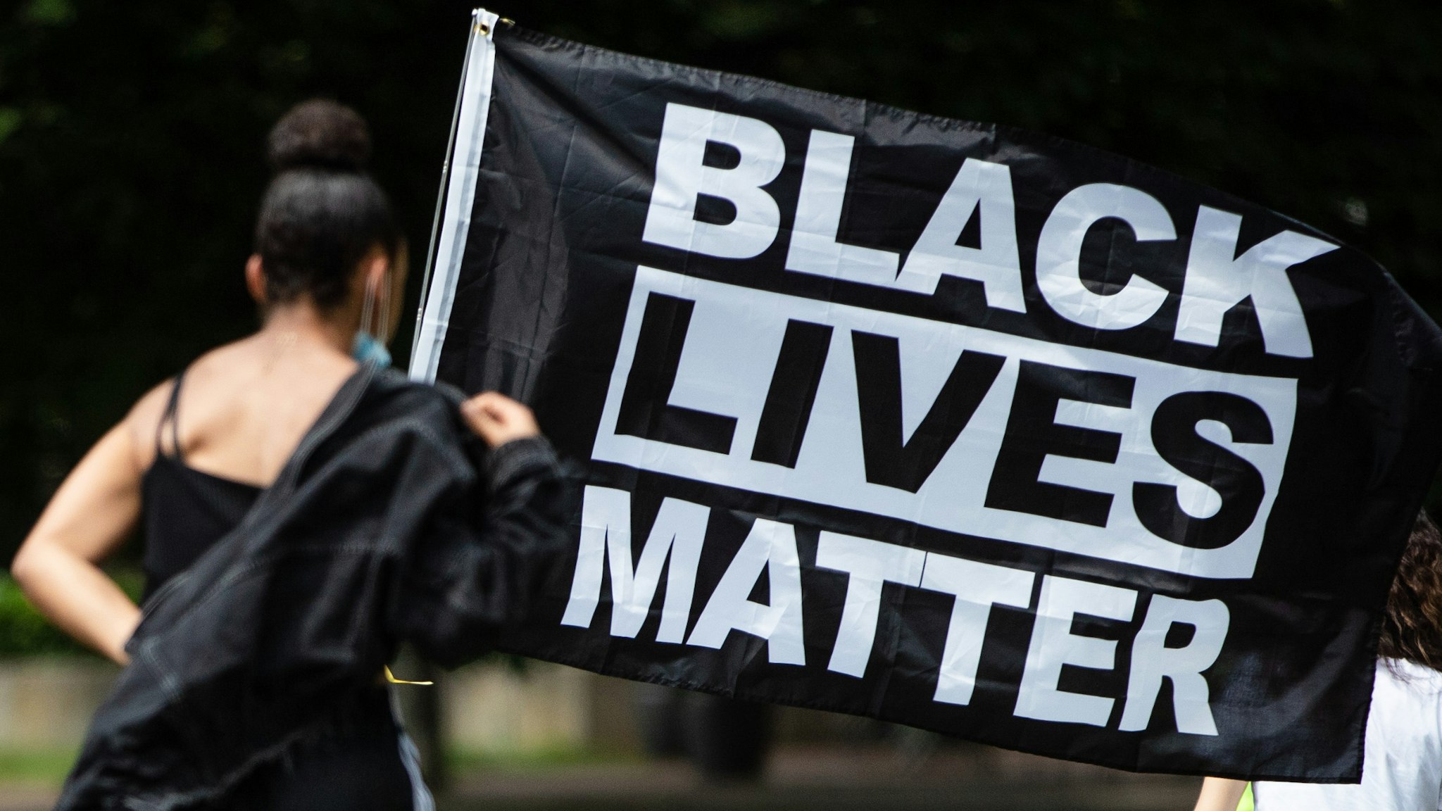 27 June 2020, Baden-Wuerttemberg, Stuttgart: "Black Lives Matter" stands in the city garden on the flag of a participant in a demonstration against racism.