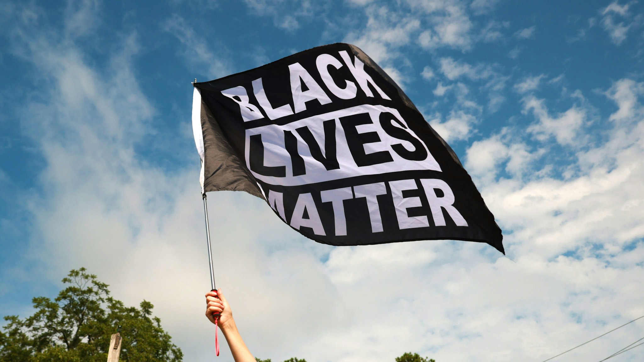 STONE MOUNTAIN, GA - AUGUST 15: A woman waves a Black Lives Matter flag during a far-right rally on August 15, 2020 near the downtown of Stone Mountain, Georgia. Georgia's Stone Mountain Park which is famous for its large rock carving of Confederate leaders planned to close on Saturday in response to a planned right-wing rally.