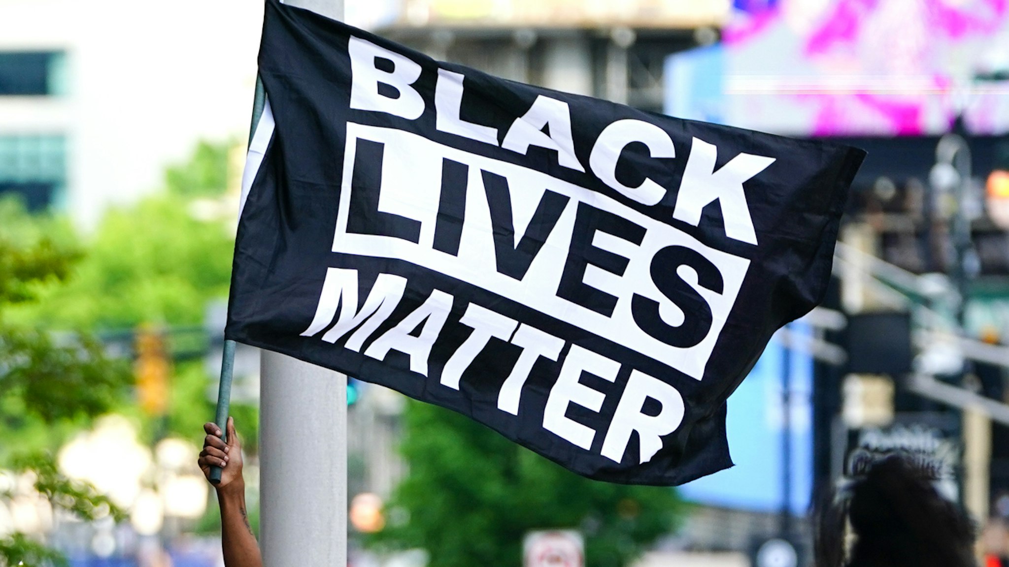 ATLANTA, GA - MAY 29: A man waves a Black Lives Matter flag during a protest on May 29, 2020 in Atlanta, Georgia. Demonstrations are being held across the US after George Floyd died in police custody on May 25th in Minneapolis, Minnesota.