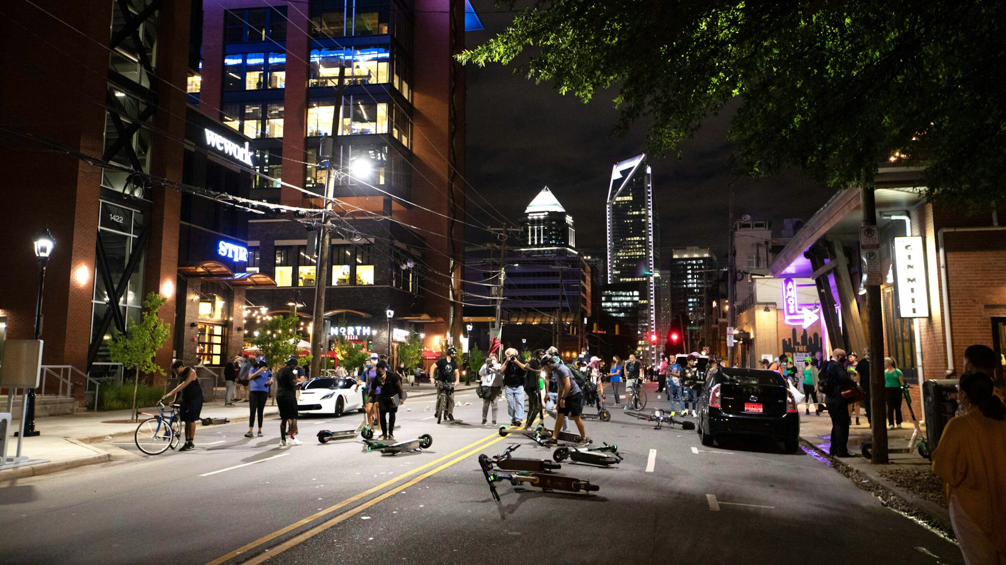 Protestors scatter e-scooters in the road in front of a complex people were eating dinner in Charlotte's South End neighborhood during a protest organized by Charlotte Uprising, in uptown Charlotte near the site of the 2020 Republican National Convention in North Carolina on August 22, 2020. - Delegates are holding private meetings inside the convention center ahead of the official start of the paired down convention on August 24.