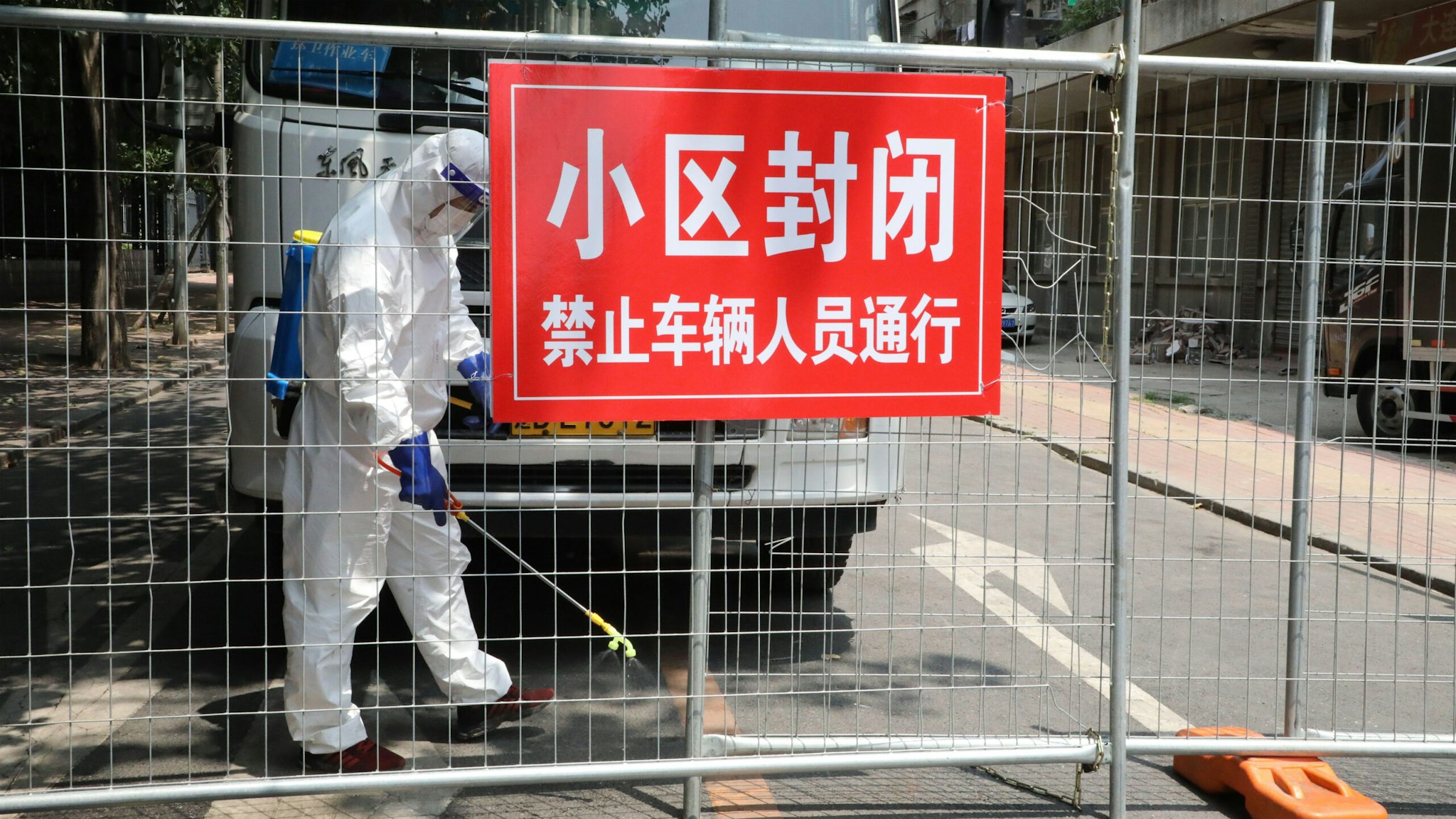 A worker wearing a protective suit sprays disinfectant at a closed residential community on July 29, 2020 in Dalian, Liaoning Province of China.