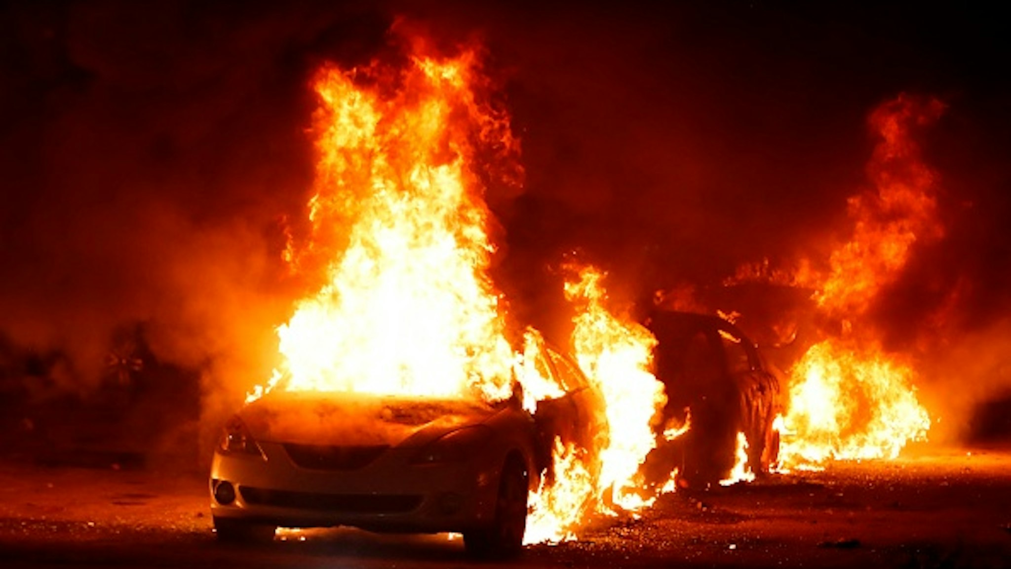 Flames roar from cars torched by protestors a few blocks from the County Court House during a demonstration against the shooting of Jacob Blake, who was shot in the back multiple times by police the day before, prompting community protests in Kenosha, Wisconsin on August 24, 2020. - Police fired tear gas on August 24 when a protest demanding racial justice in the city of Kenosha in Wisconsin turned violent, as rage builds once more in the US at the shooting of a black man by a white officer.