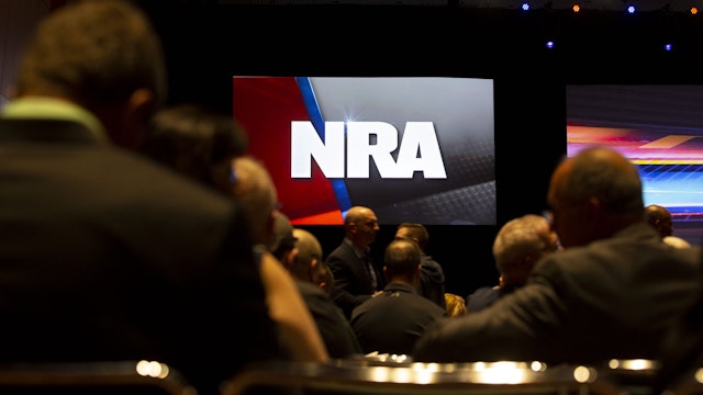 An National Rifle Association (NRA) logo is displayed above members during the NRA annual meeting of members in Indianapolis, Indiana, U.S., on Saturday, April 27, 2019. Retired U.S. Marine Corps Lieutenant Colonel Oliver North has announced that he will not serve a second term as the president of the NRA amid inner turmoil in the gun-rights group. Photographer: Daniel Acker/Bloomberg via Getty Images