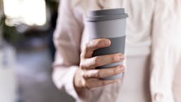 close-up of a businesswoman holding recycable takeaway coffee cup woman holding coffee