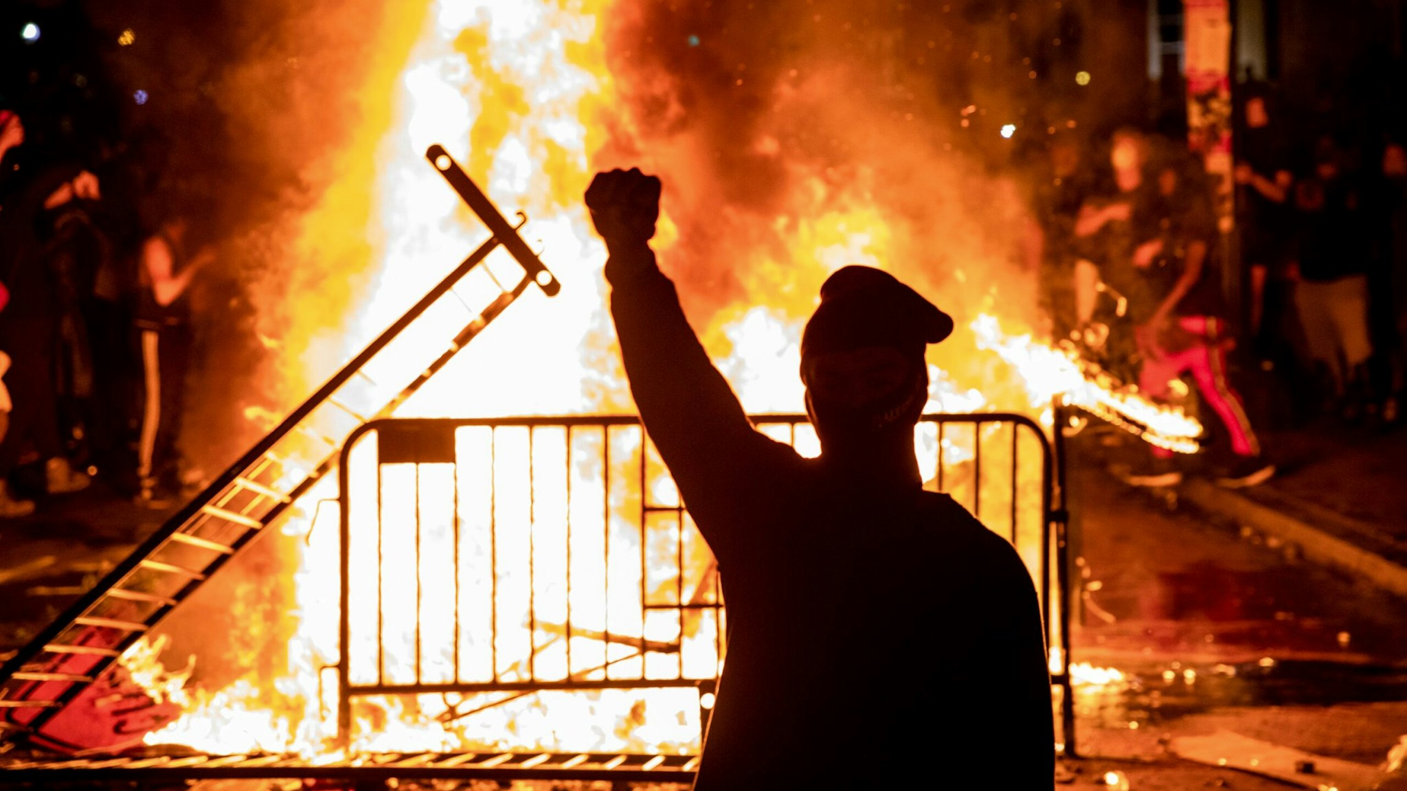 TOPSHOT - A protester raises a fist near a fire during a demonstration outside the White House over the death of George Floyd at the hands of Minneapolis Police in Washington, DC, on May 31, 2020. - Thousands of National Guard troops patrolled major US cities after five consecutive nights of protests over racism and police brutality that boiled over into arson and looting, sending shock waves through the country. The death Monday of an unarmed black man, George Floyd, at the hands of police in Minneapolis ignited this latest wave of outrage in the US over law enforcement's repeated use of lethal force against African Americans -- this one like others before captured on cellphone video. (Photo by Samuel Corum / AFP) (Photo by SAMUEL CORUM/AFP via Getty Images)