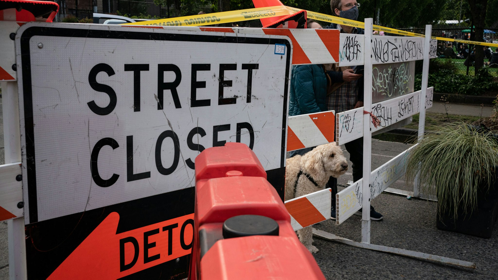 SEATTLE, WA - JUNE 10: People peer through a barrier with their dog at an entrance to the so-called "Capitol Hill Autonomous Zone" on June 10, 2020 in Seattle, Washington. The zone includes the blocks surrounding the Seattle Police Departments East Precinct, which was the site of violent clashes with Black Lives Matter protesters, who have continued to demonstrate in the wake of George Floyds death. (Photo by David Ryder/Getty Images)
