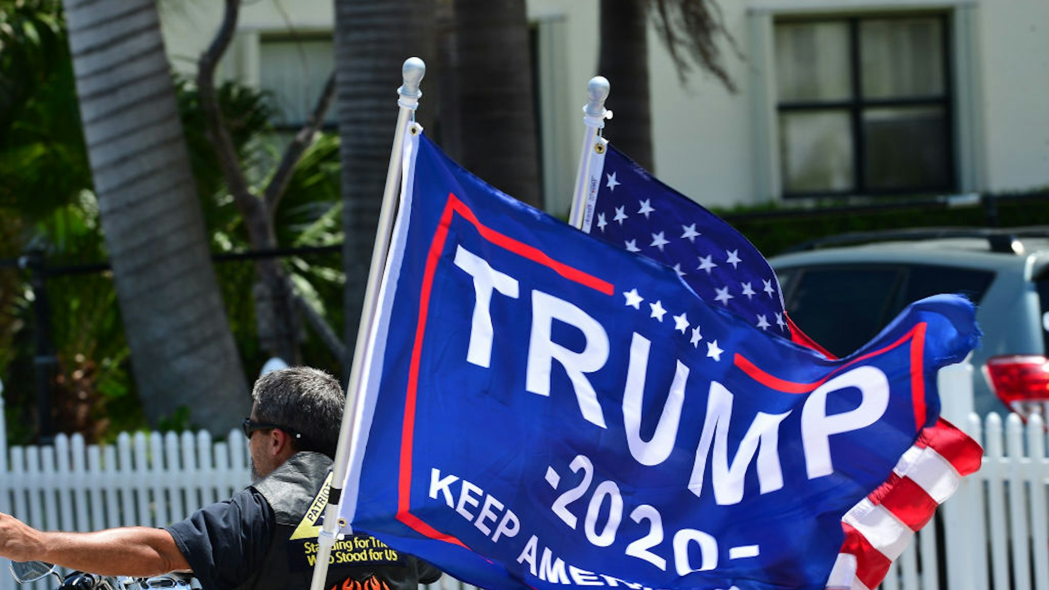 Supporters of President Donald Trump wave their flags as a Flotilla of Boaters sail by on inter-coastal waterways at Mar-a-Lago to mark the President's 75th birthday on June 14, 2020 in Palm Beach, Florida.