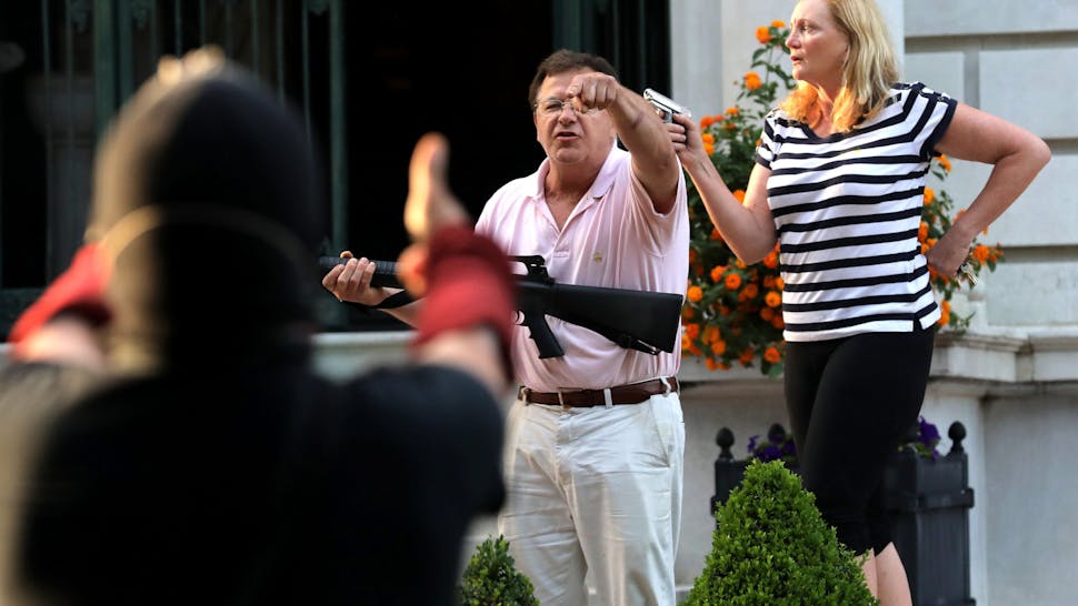 Armed homeowners Mark T. and Patricia N. McCloskey stand in front their house along Portland Place as they confront protesters marching to St. Louis Mayor Lyda Krewson's house Sunday, June 28, 2020, in the Central West End of St. Louis. The protesters called for Krewson's resignation for releasing the names and addresses of residents who suggested defunding the police department. (Laurie Skrivan/St. Louis Post-Dispatch/Tribune News Service via Getty Images)