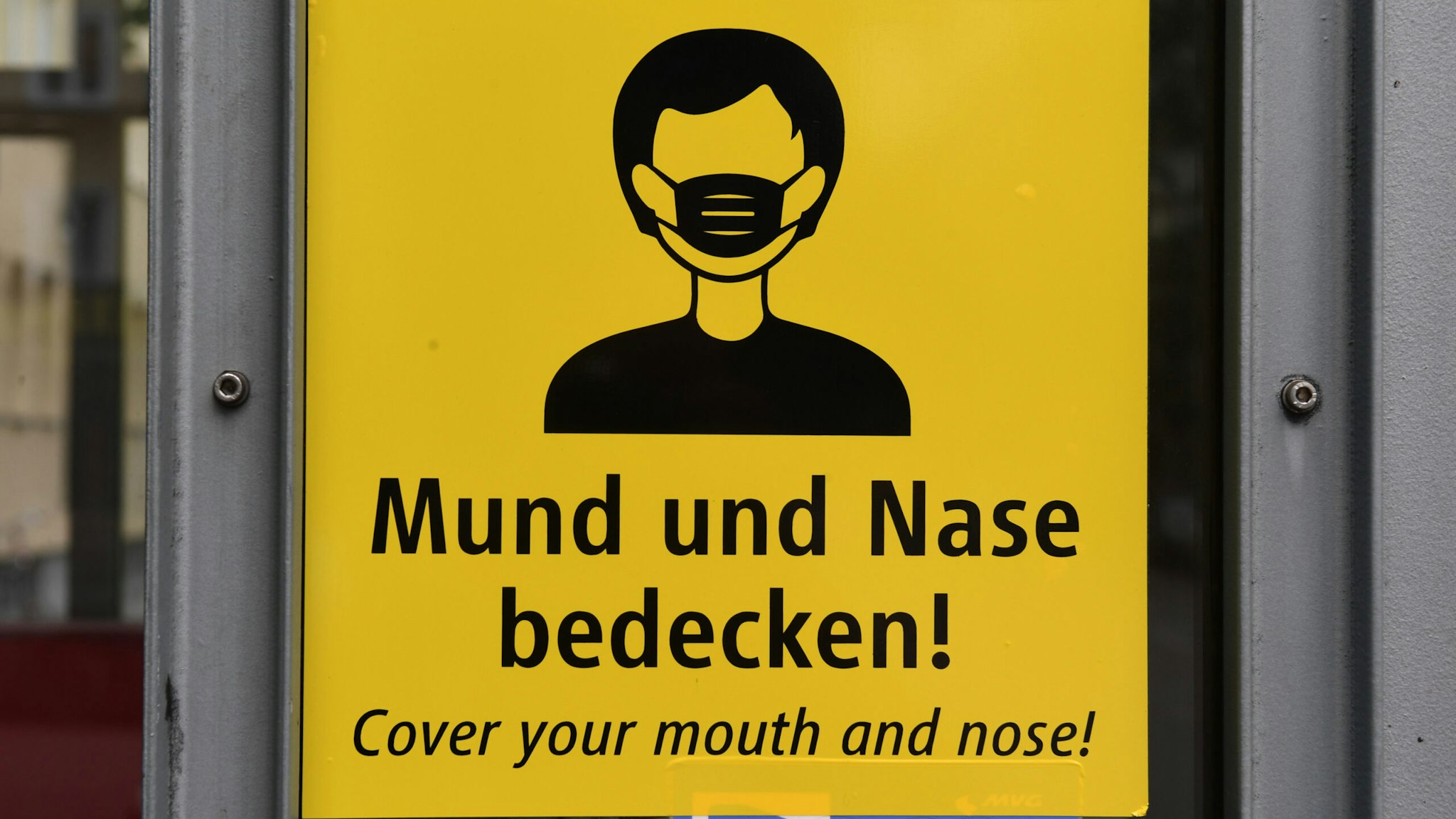 02 August 2020, Bavaria, Munich: A sign with the inscription "Cover your mouth and nose" can be seen on an elevator at the Theresienstraße subway station. Photo: Felix Hörhager/dpa (Photo by Felix Hörhager/picture alliance via Getty Images)
