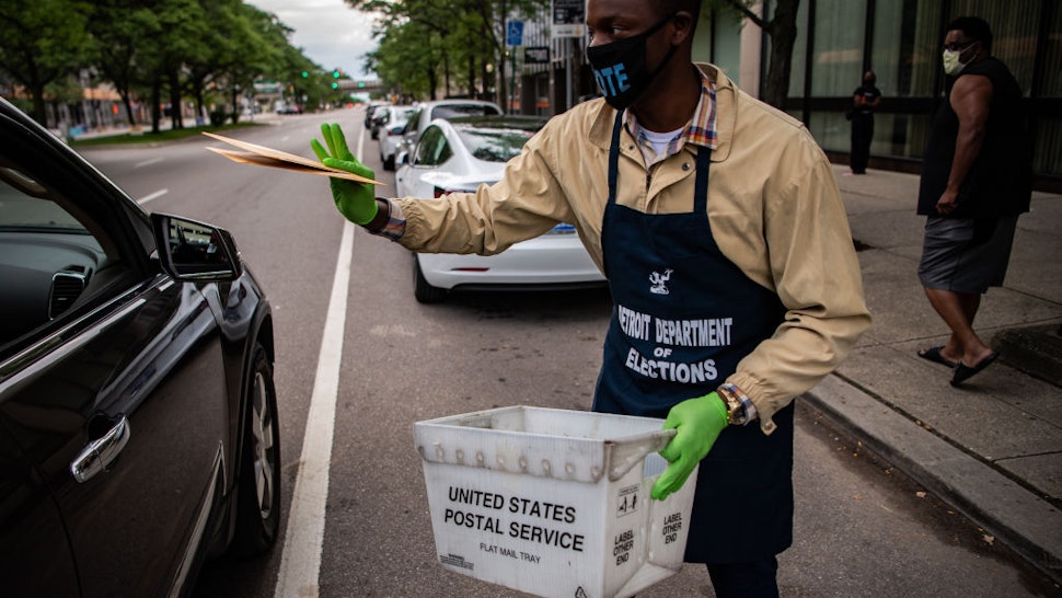 Demario Thurmond, 23, staff with the Detroit Department of Elections collects absentee ballots from a voter during Michigan Primary in Detroit, Michigan on Tuesday, August 4, 2020.