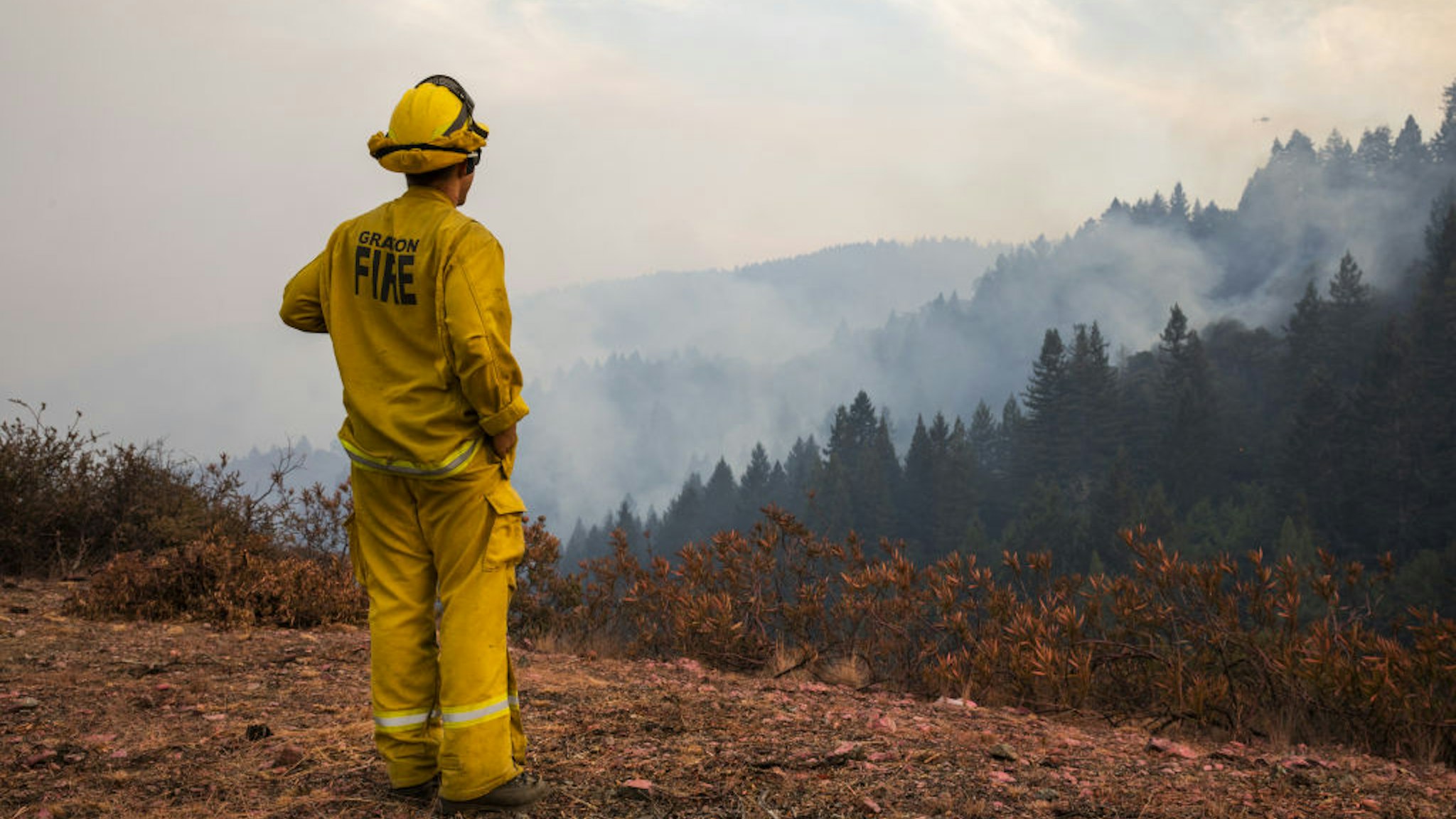 Dustin Blumenthal of the Graton Fire Department watches over spot fires on Big Ridge, seen smoldering in the background, during the Walbridge portion of the LNU Lightning Complex fire in Sonoma County, California, U.S., on Saturday, Aug. 22, 2020. More than 360 blazes are burning in California, forcing mass evacuations in the northern part of the state and creating an air quality emergency. Photographer: Philip Pacheco/Bloomberg via Getty Images