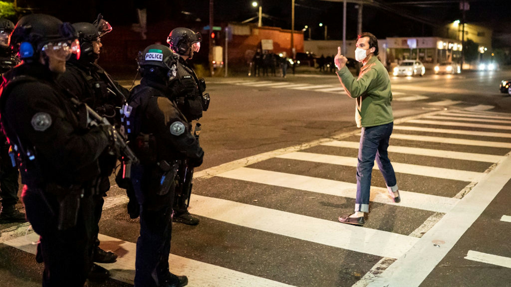 A protester makes a hand gesture toward Portland police officers after they dispersed a crowd from in front of the Portland Police Association (PPA) building early in the morning on August 29, 2020 in Portland, Oregon.